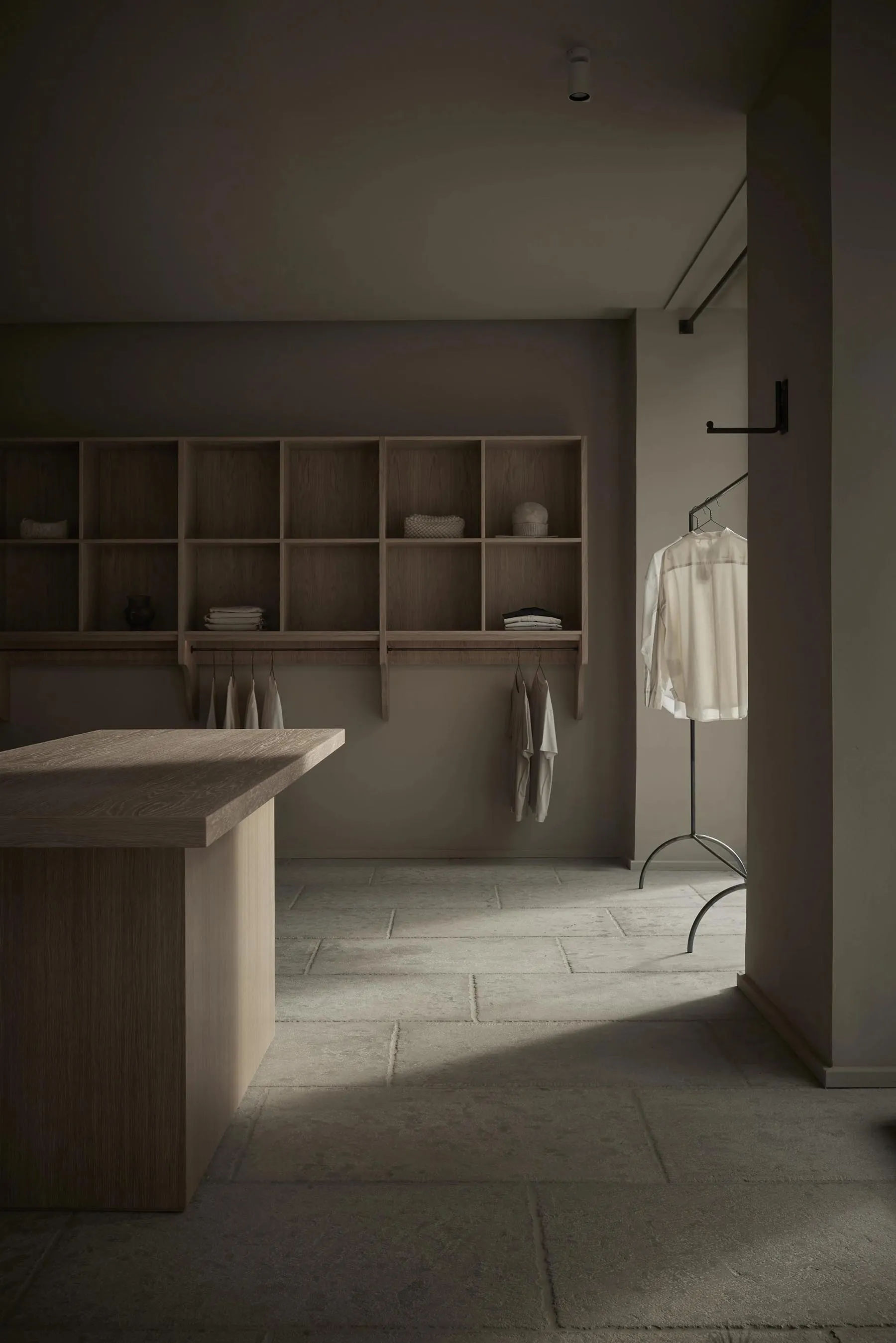 A minimalist wardrobe space featuring wooden shelves and hanging clothes.