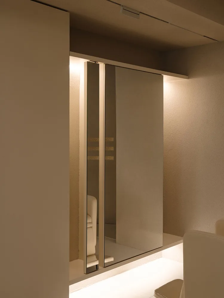A minimalist wardrobes area with mirrored panels, white walls and ceiling.