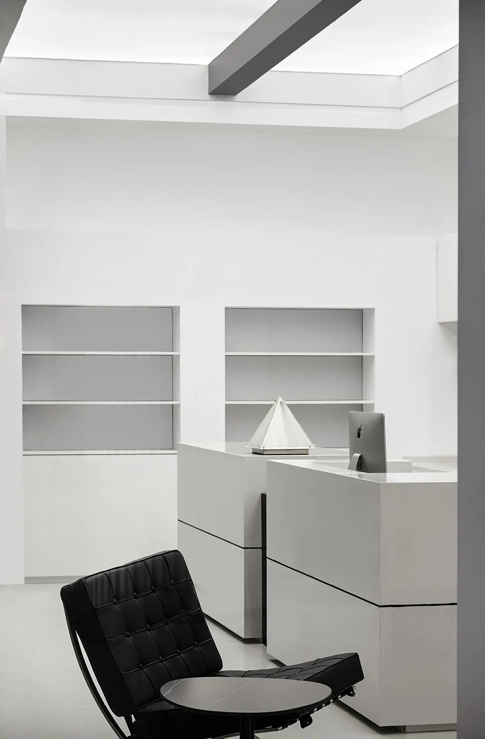 A modern office space featuring black and white decor, white furniture, and concrete elements.