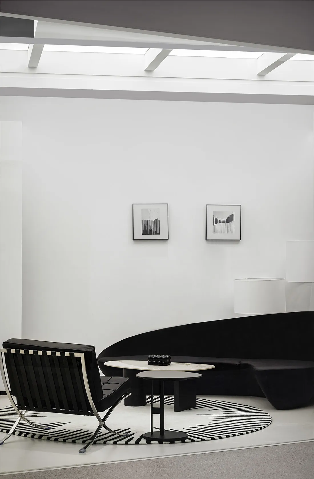 A modern living room with a black leather sofa, metal chair, and stone coffee table.