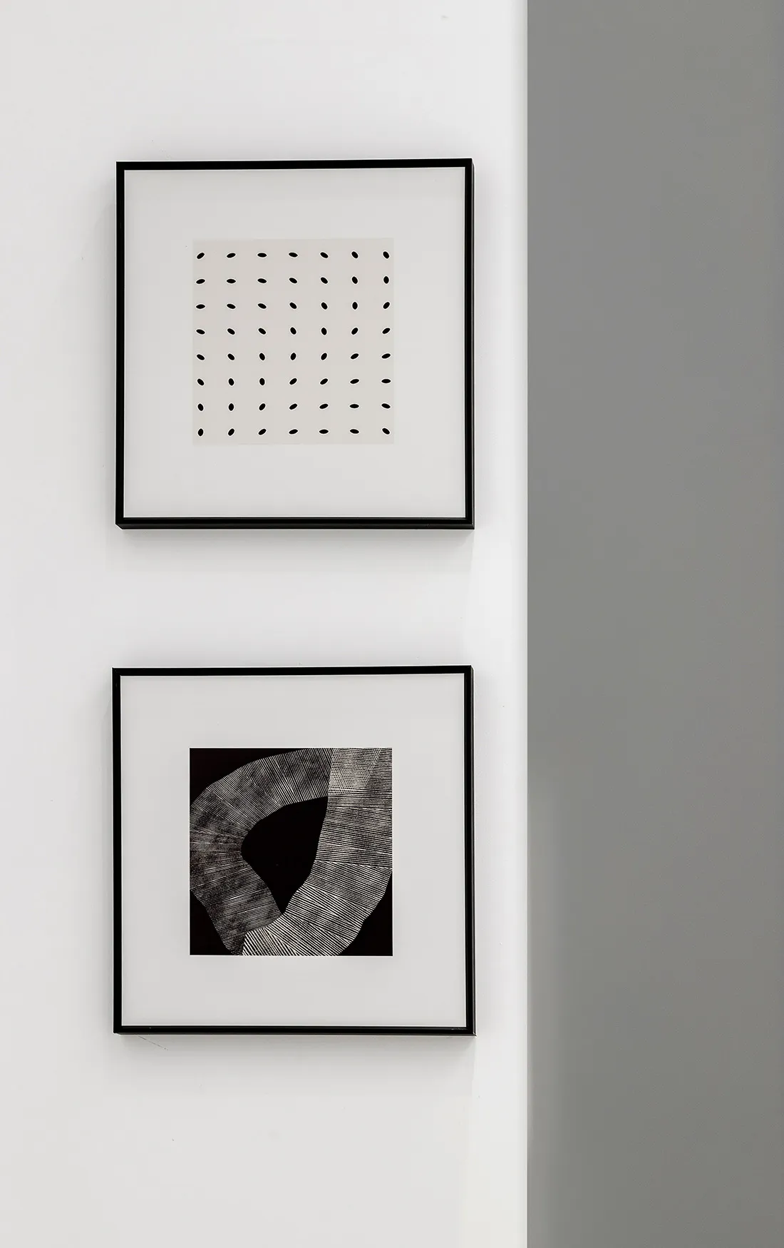 Two minimalist black and white abstract art prints mounted on a white wall.