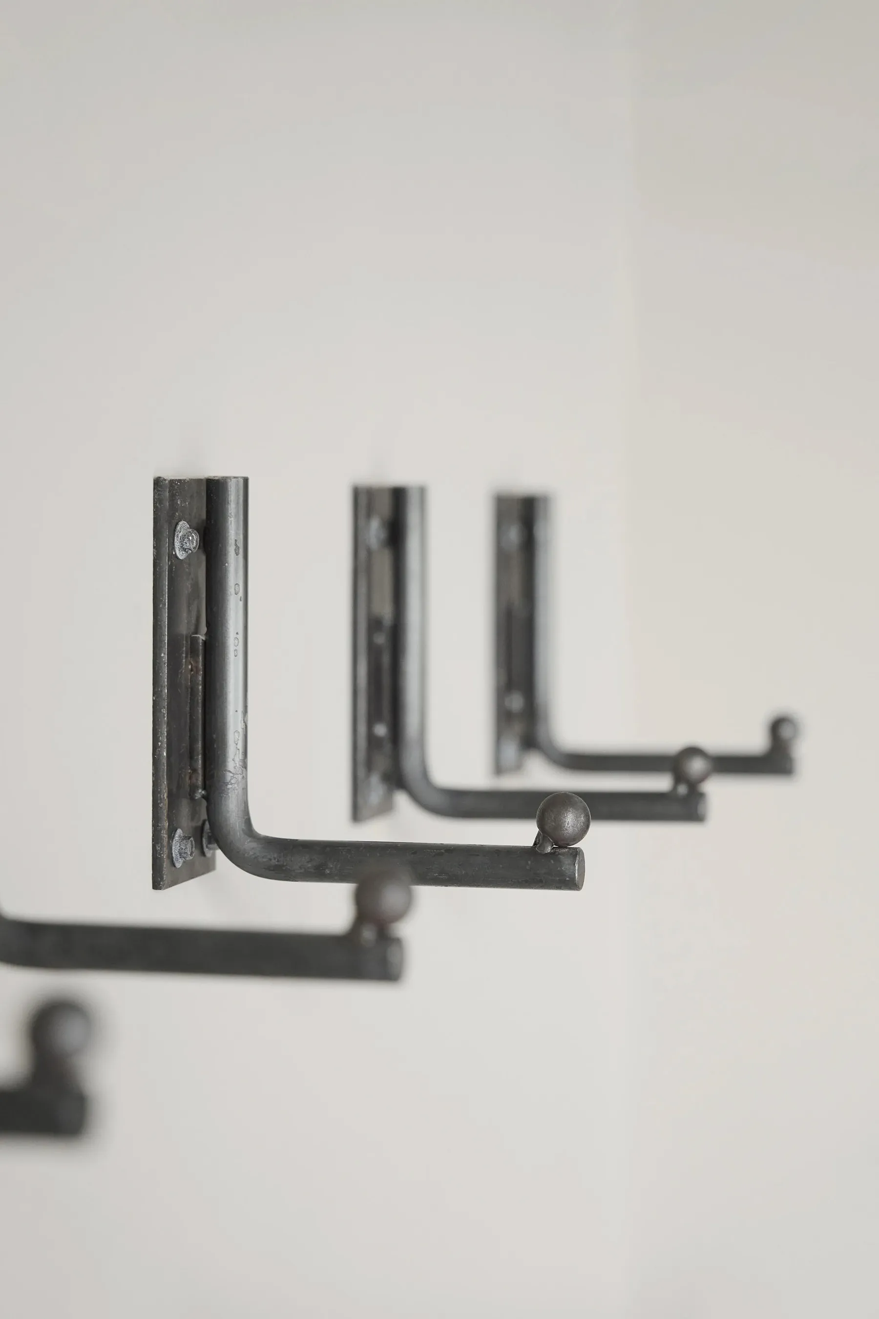 Three metal hooks mounted on a white wall, featuring a modern industrial design.