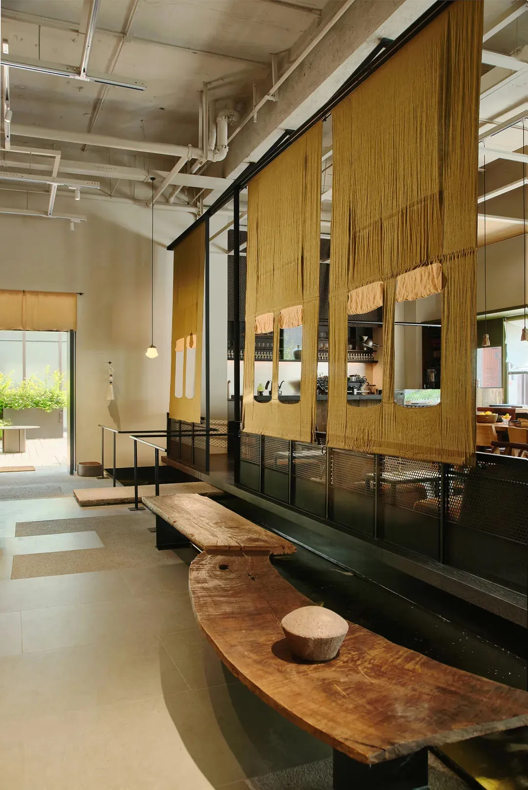Interior of an industrial-style restaurant featuring wooden and metallic elements and fabric dividers.