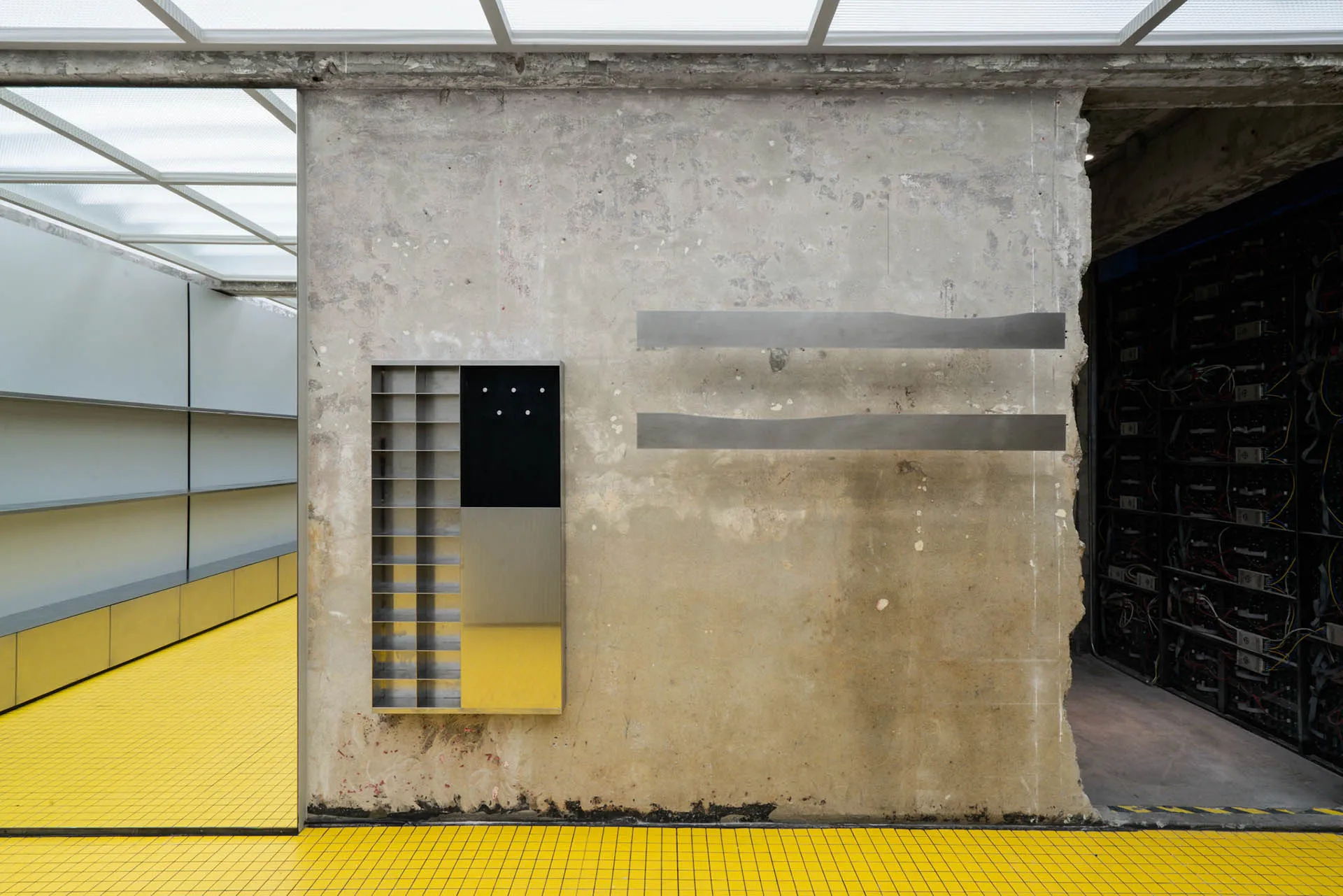 A minimalist space featuring concrete walls and floors with a metal bookshelf。