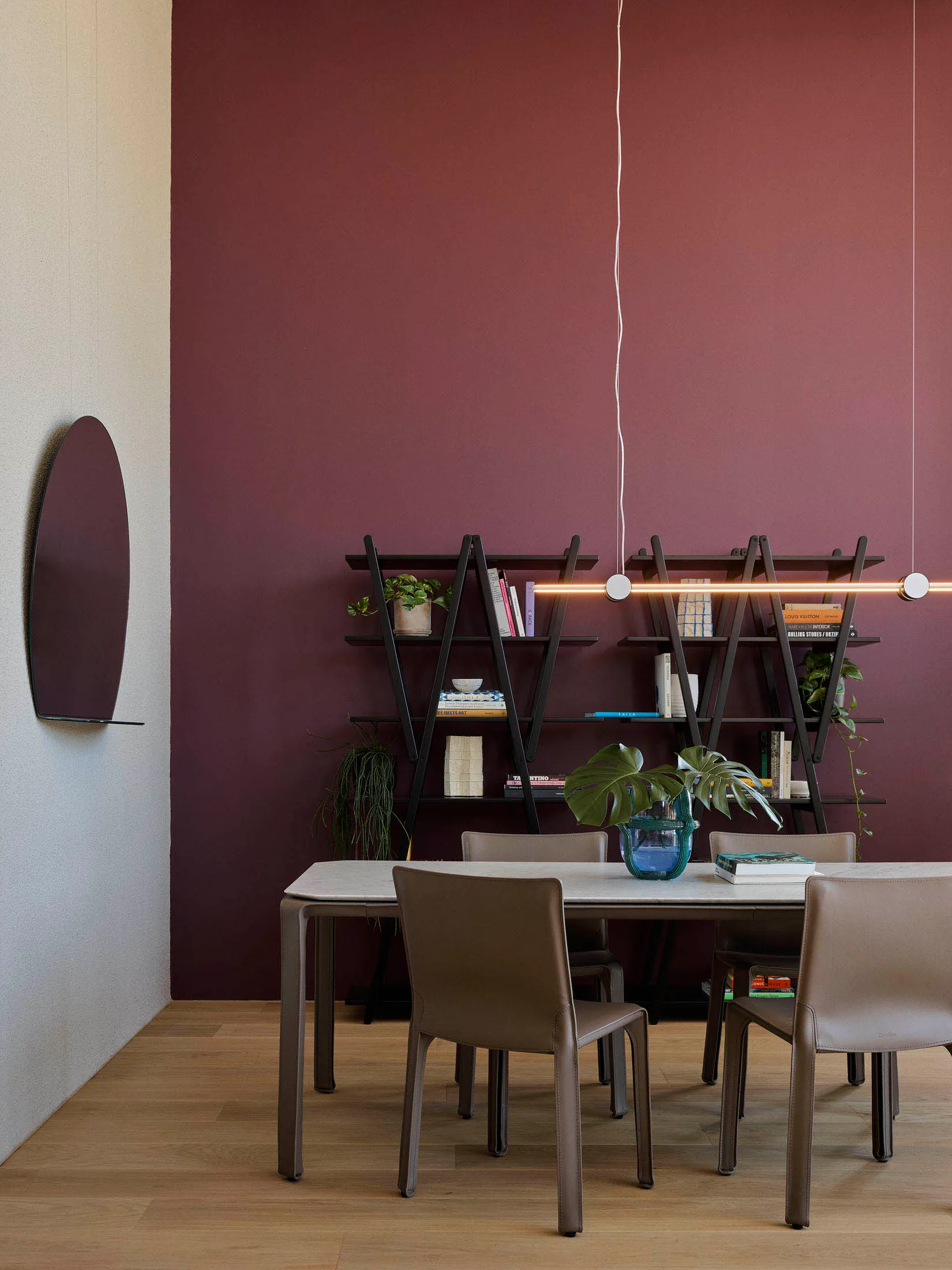 Modern dining room featuring a white table with metal legs, metal shelves, and leather chairs.