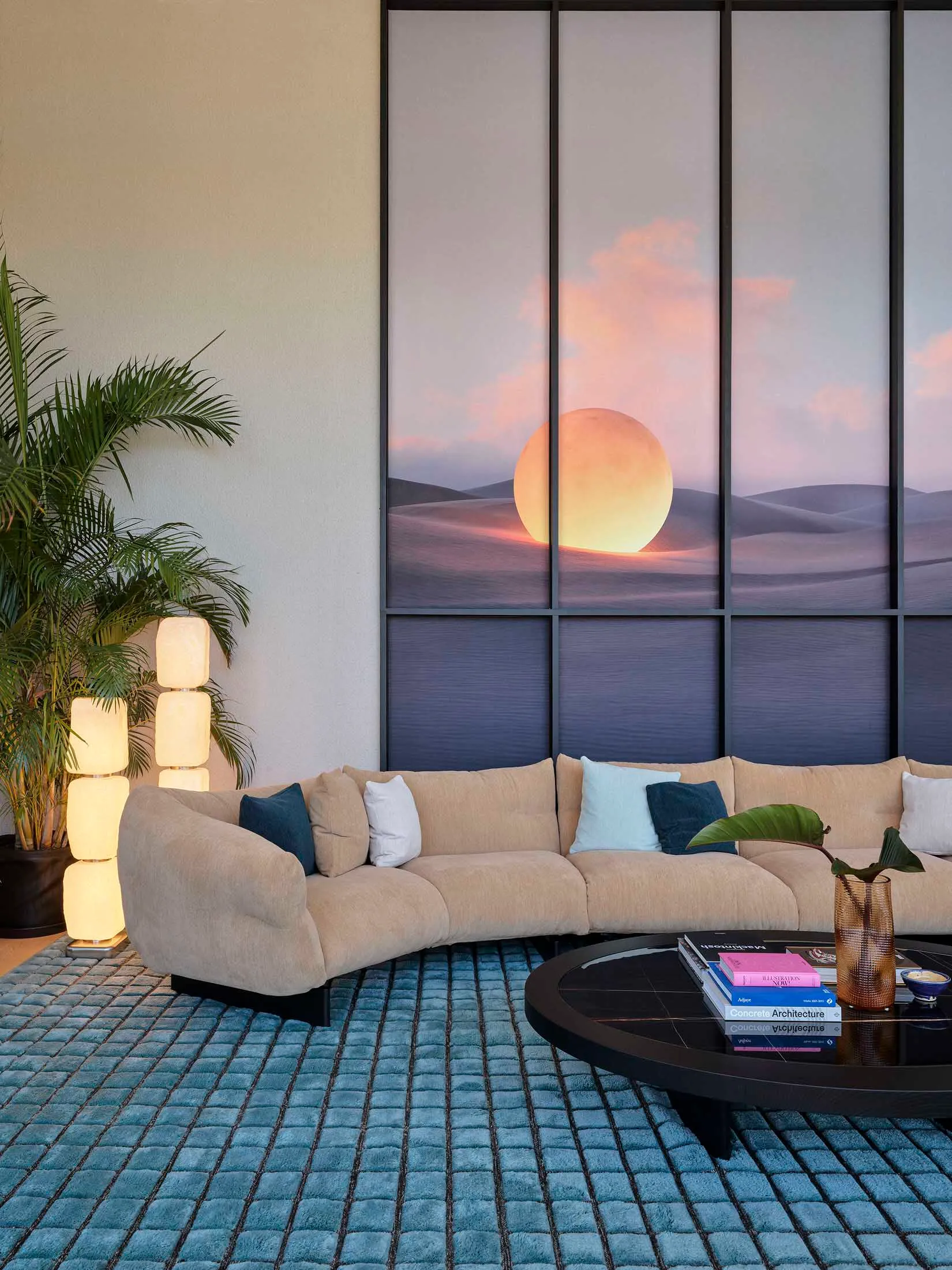 A modern living room with a neutral-toned fabric sofa, curved floor lamp, and a round glass-topped coffee table.
