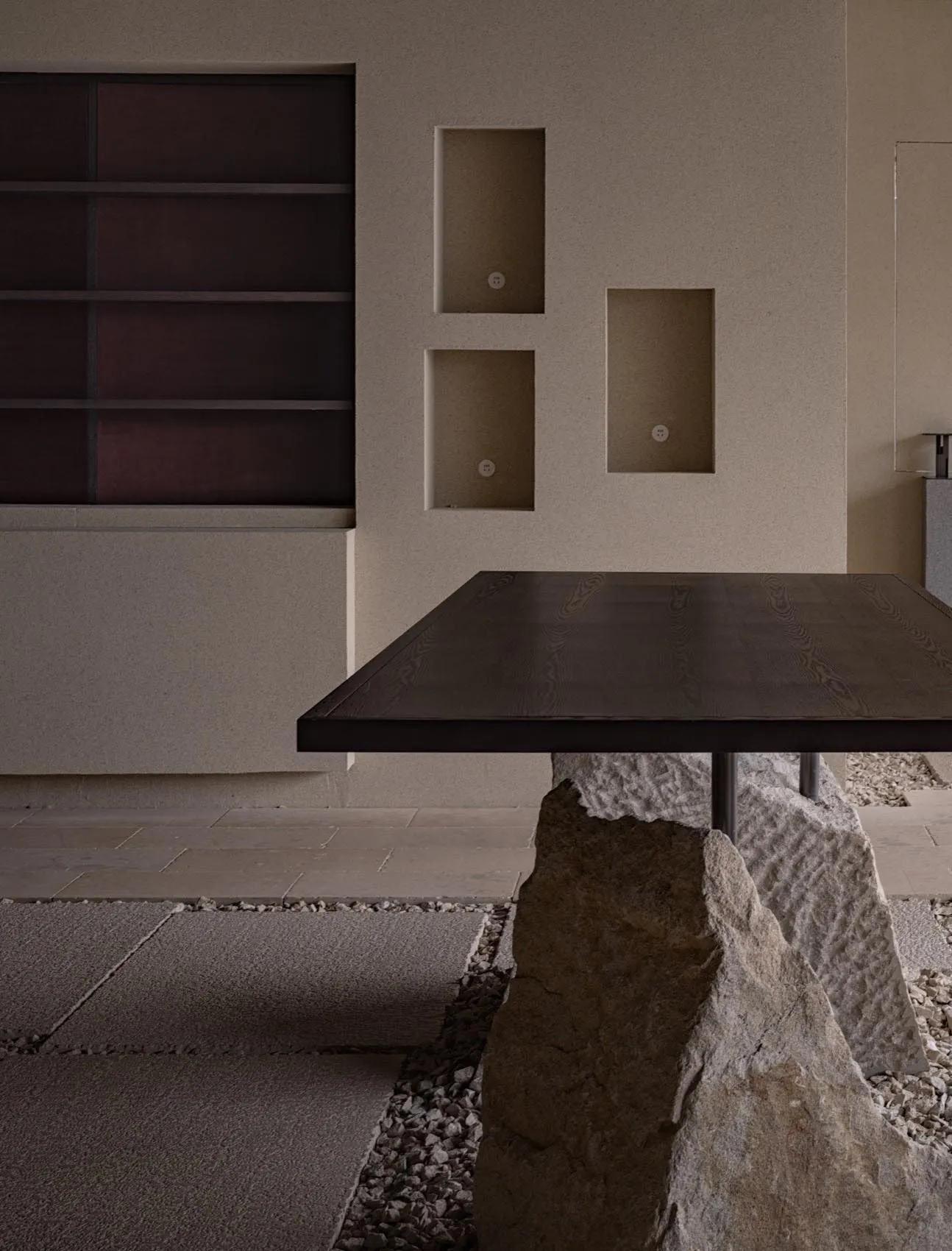 A minimalist interior space featuring a stone table against a modern wall with built-in shelves.