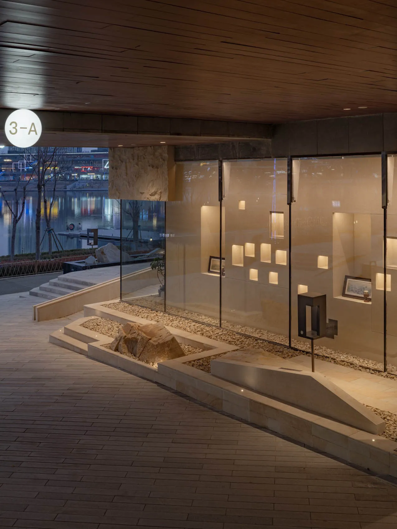 A sleek modern gallery space featuring glass walls, exposed brick, and stone elements.