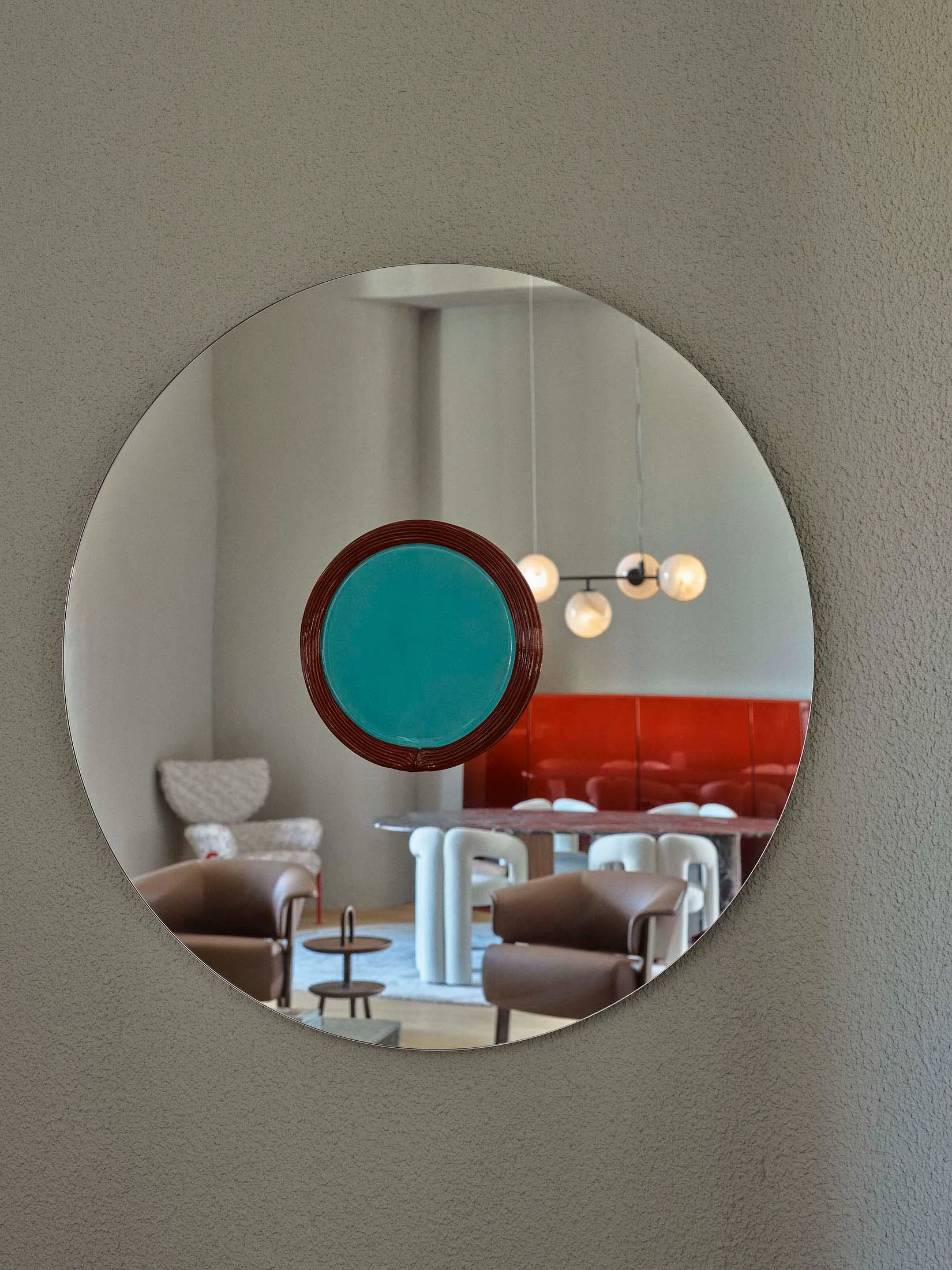 A modern interior design featuring a round mirror with a metal frame, reflecting a contemporary space with furniture and ligh