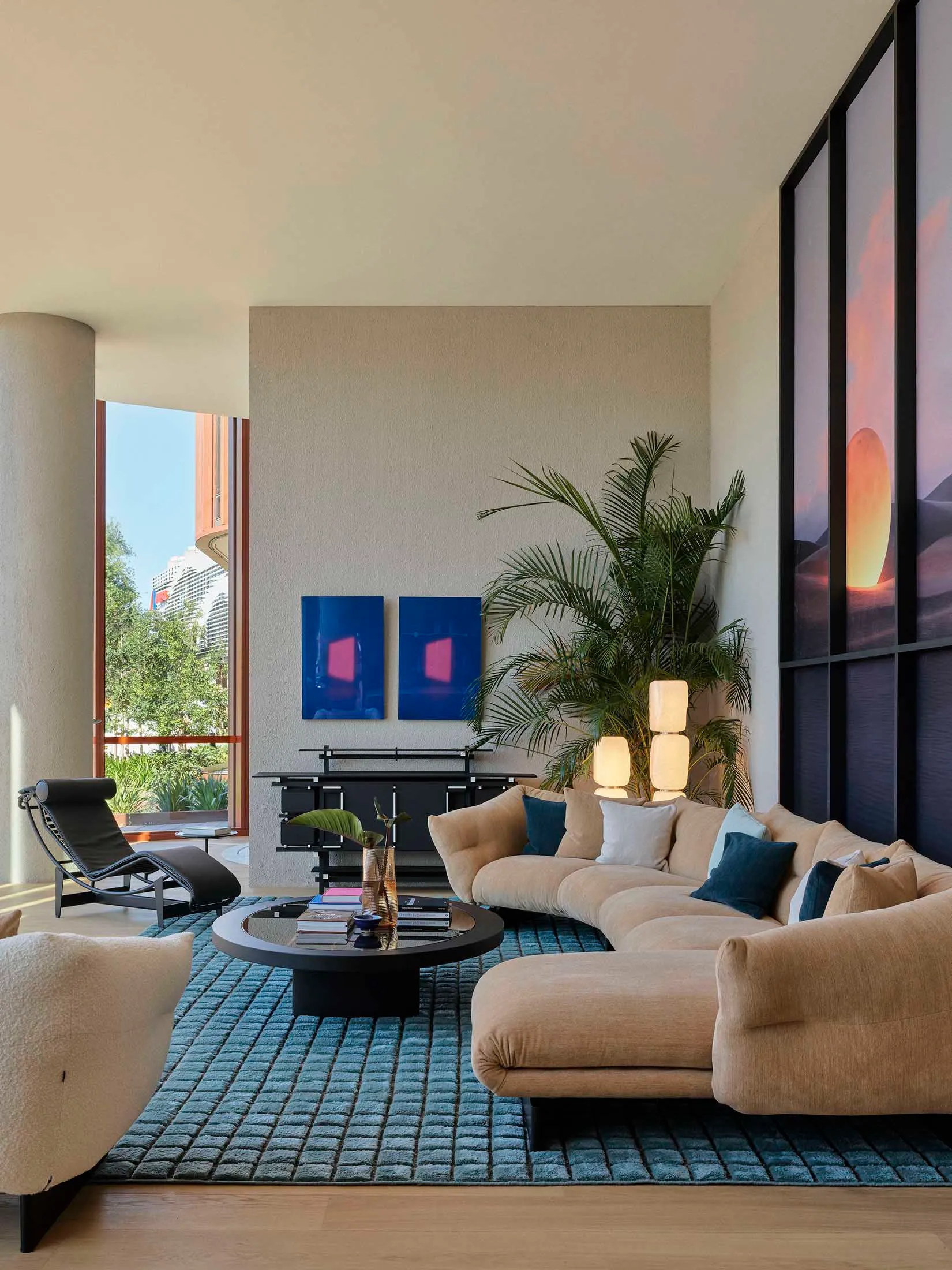 A modern living room featuring a sectional sofa upholstered in fabric and surrounded by a glass coffee table, wood flooring,