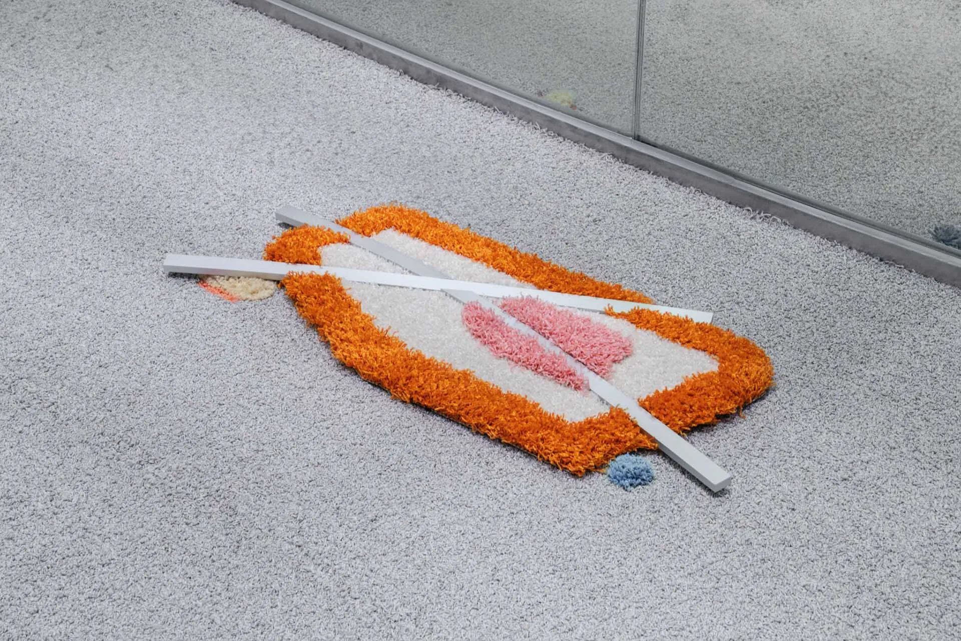 A decorative textile object with white, blue, and orange hues lying on a carpeted floor.