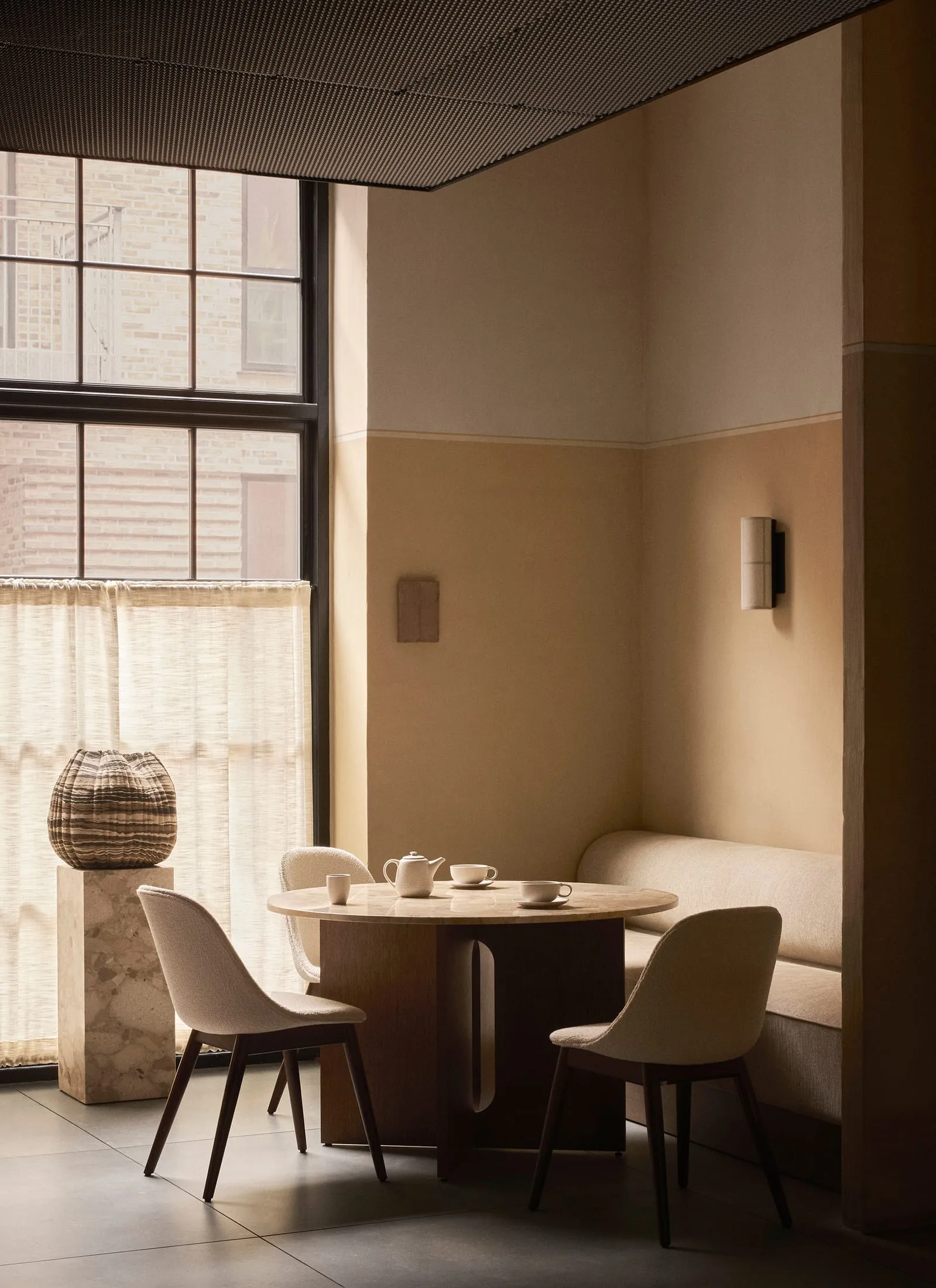 A cozy minimalist cafe interior featuring marble accents, fabric seating, and metal furnishings.