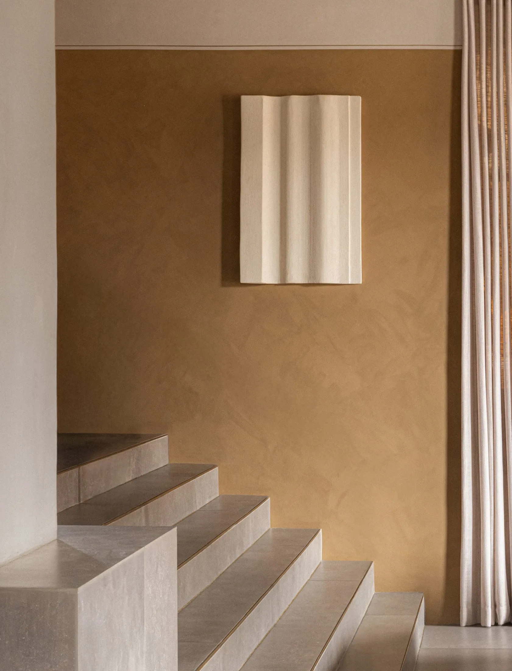 Minimalist staircase with concrete steps and a textured plaster wall