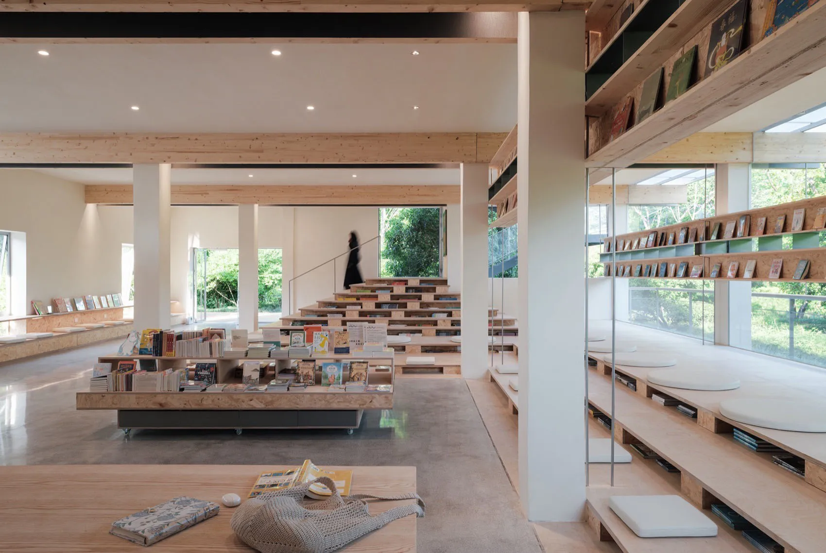 A modern library interior with wooden shelving and concrete flooring.