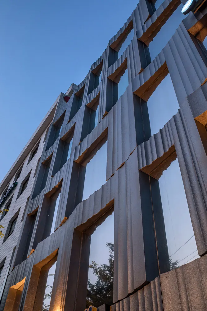 Modern metal building façade with geometric patterns against a blue sky.