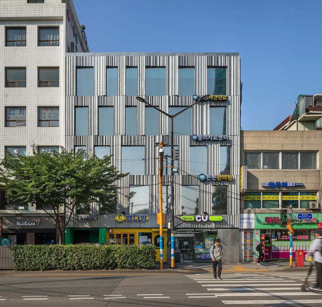 一座擁有金屬外牆板的現代辦公大樓，位於都市環境中。