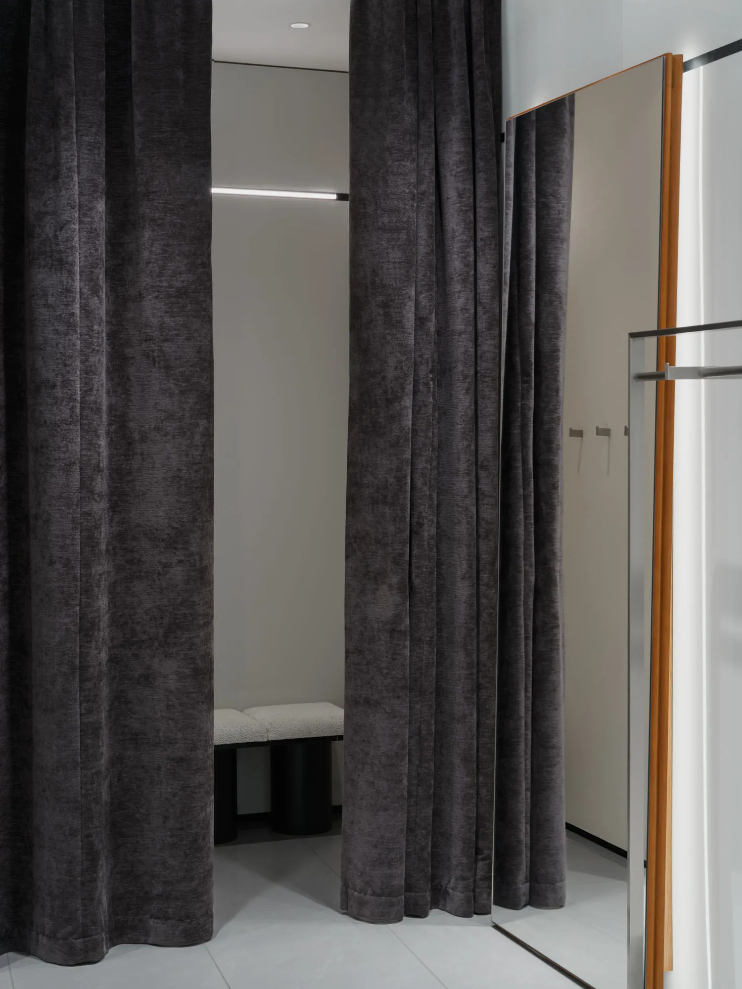 A fashion retail store with velvet curtains and a dressing room.