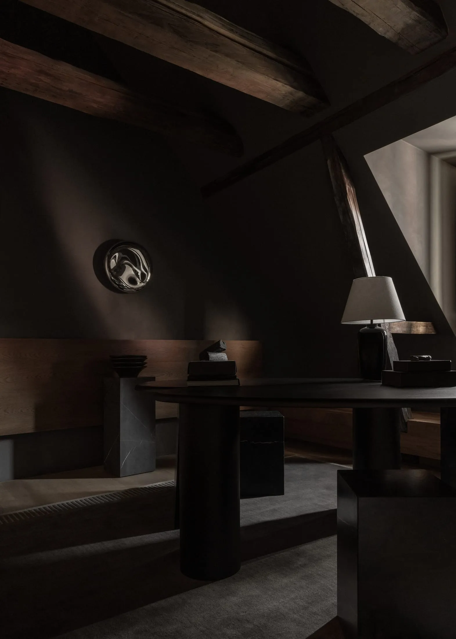 A modern minimalist office space with dark walls, wooden beams, and a sleek desk