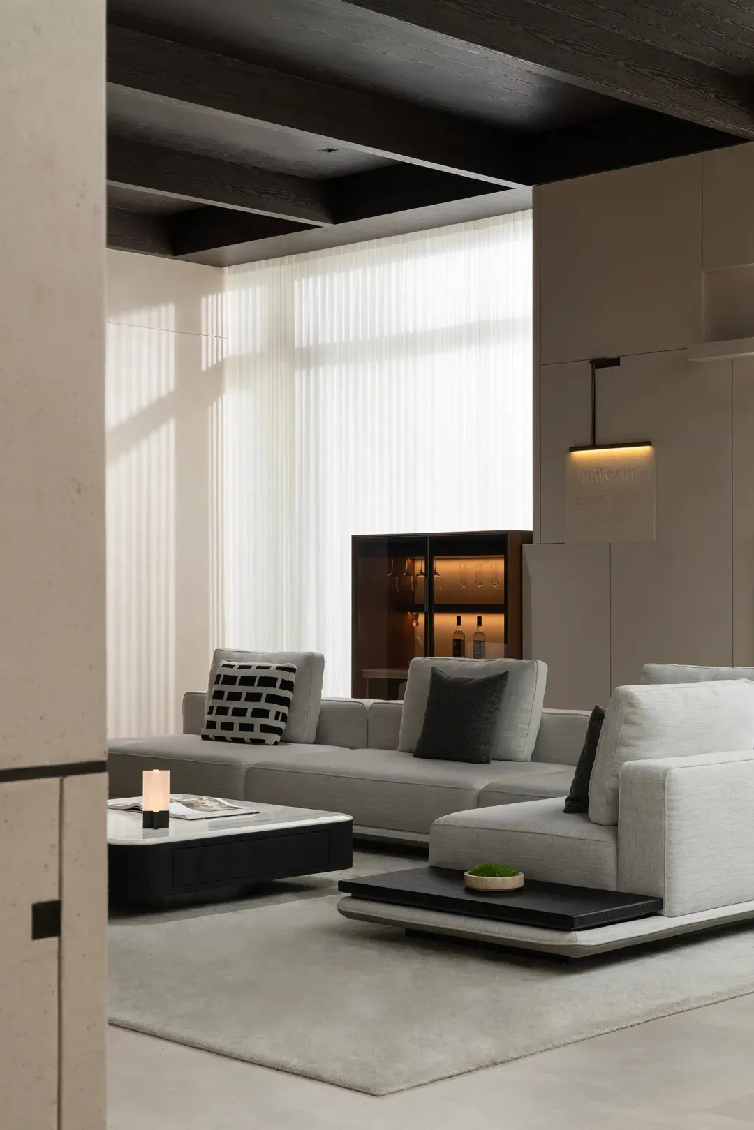 A modern living room featuring a fabric sofa with wooden accents and a chalkboard desk, illuminated by natural light through
