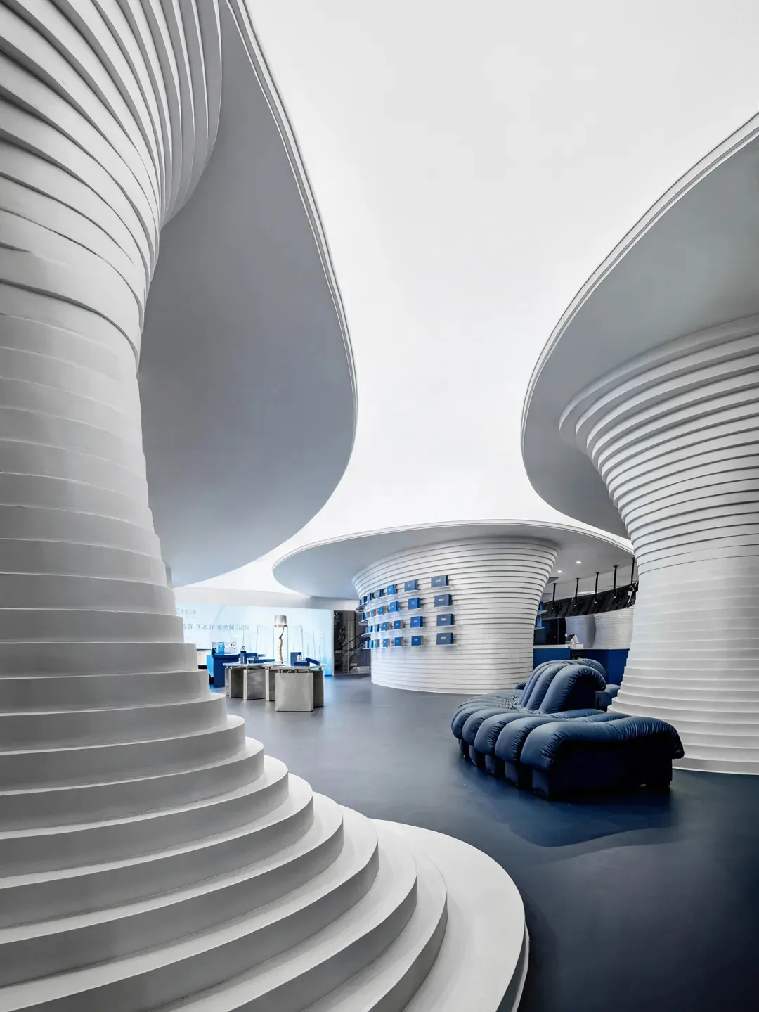Modern interior space with white tiled walls and floors, featuring contemporary furniture and minimalist design.