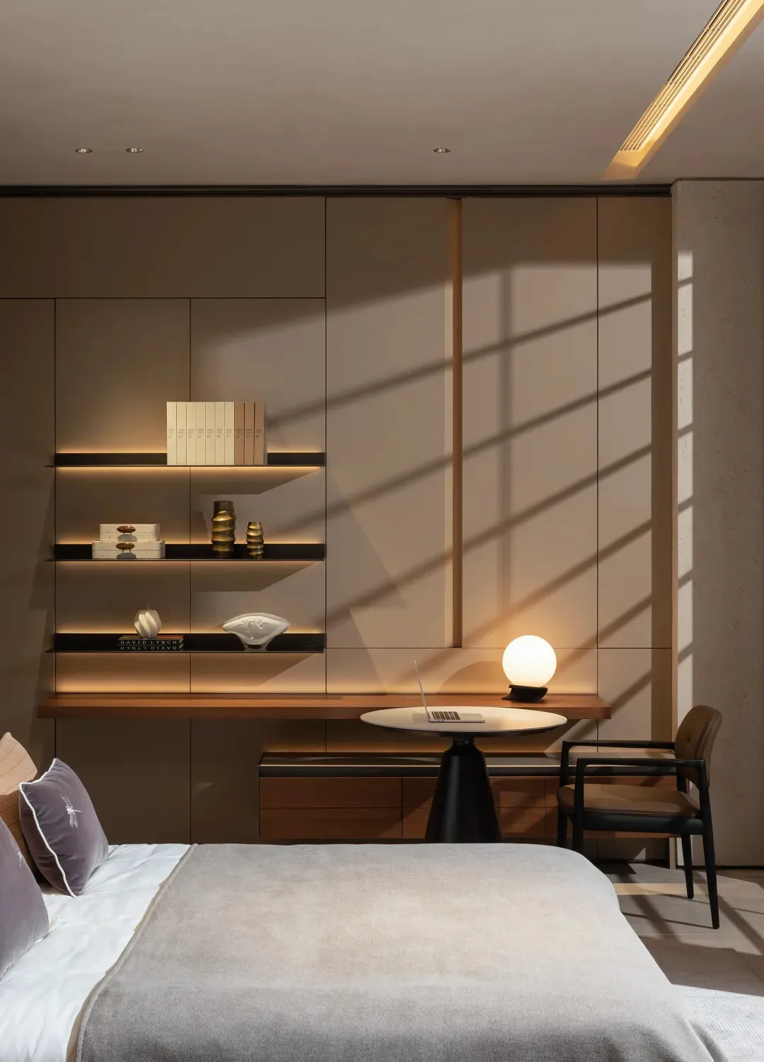 Modern minimalist bedroom featuring glass shelves, a wooden desk, and a metal lamp.