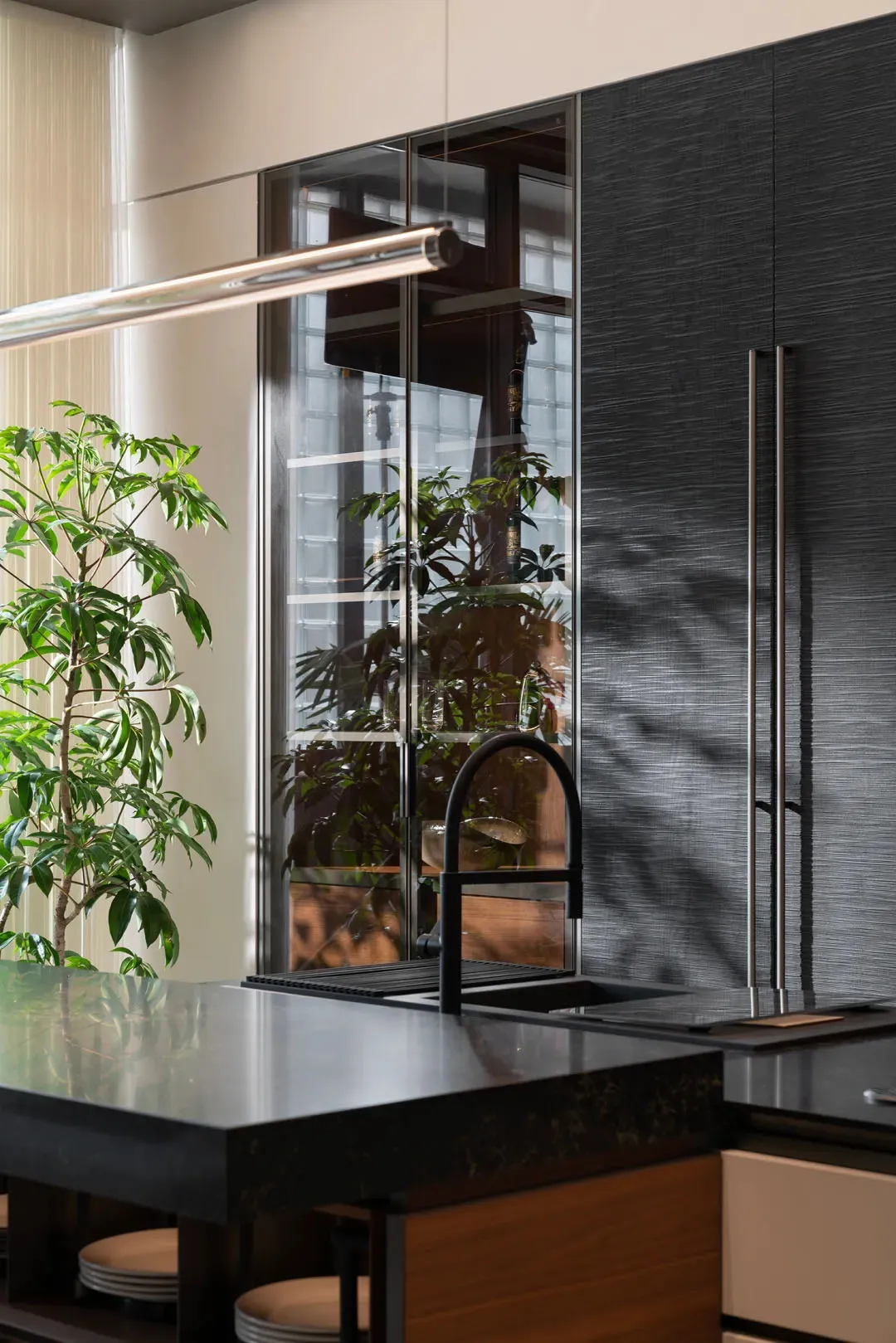 Modern residential kitchen featuring sleek black stone countertops and glass cabinetry.