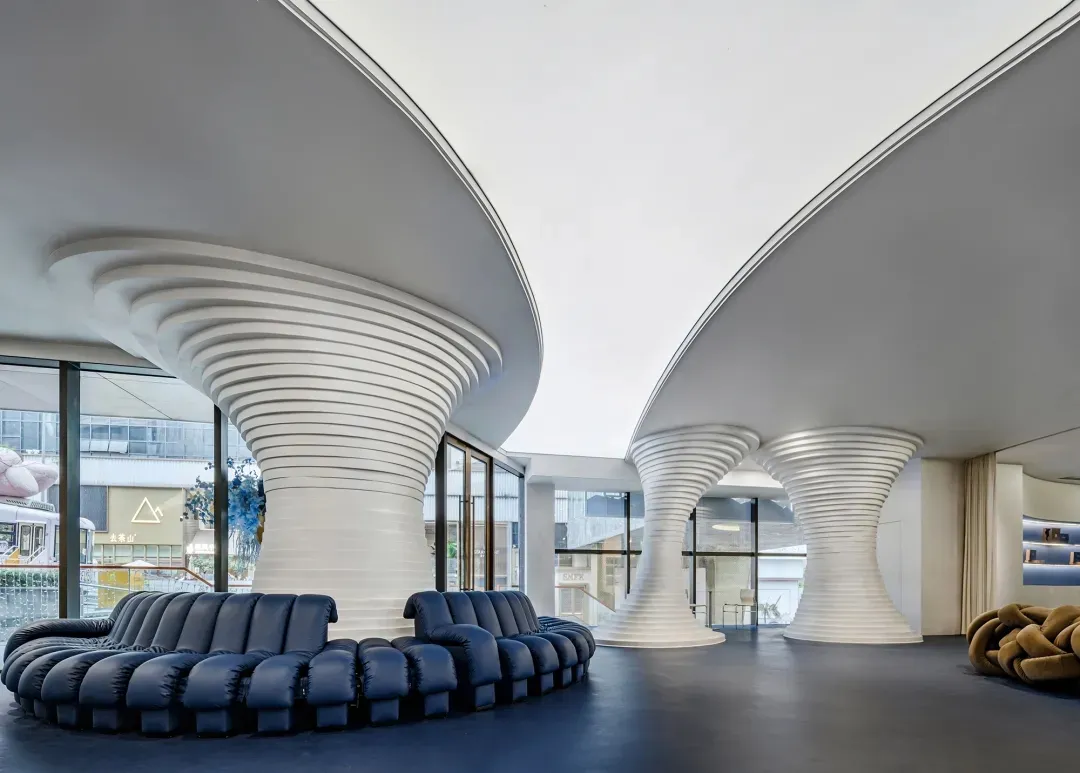 A modern retail storefront featuring curved white structures and a blue sofa in the foreground.