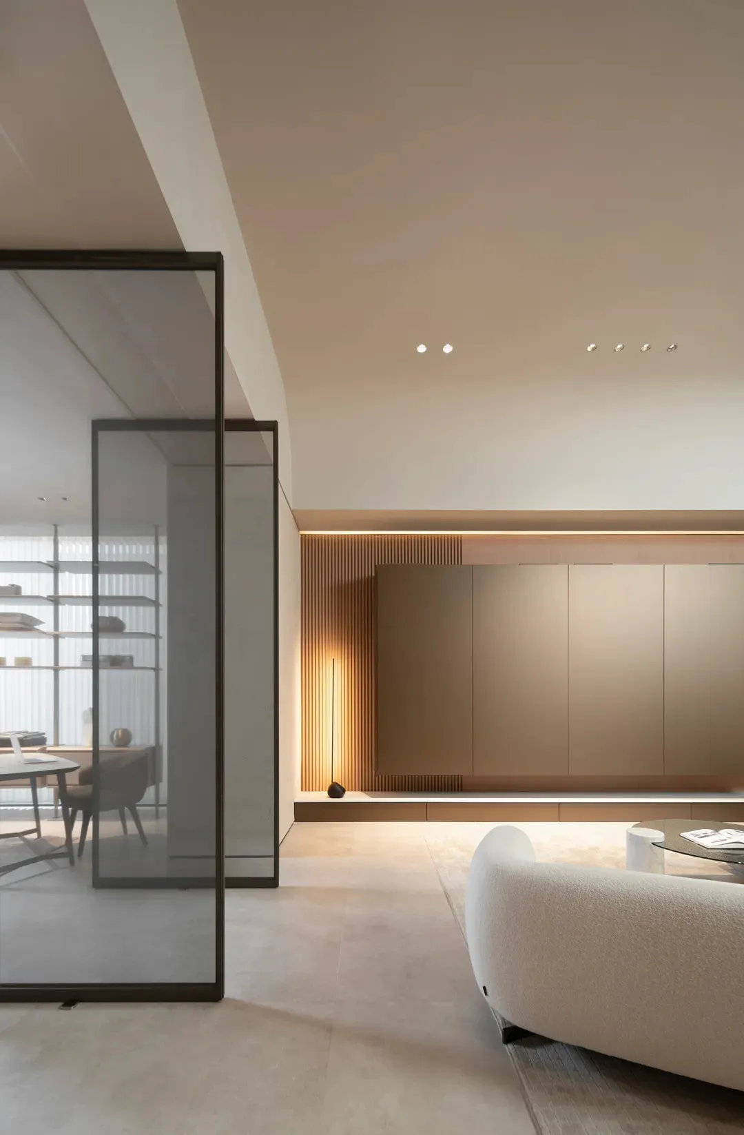 A modern minimalist living room with light-colored flooring, wooden paneling, and a white sofa.