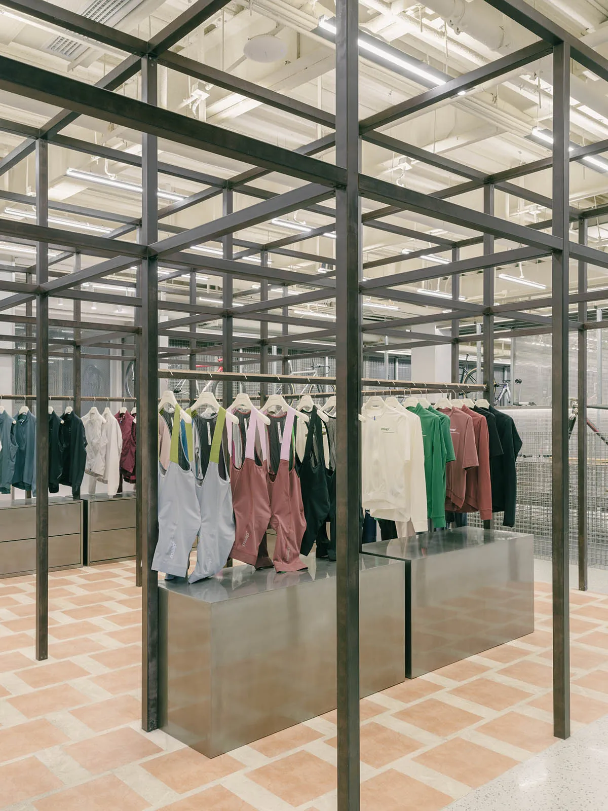 A modern retail shop with a metal frame structure and concrete flooring display clothing items.
