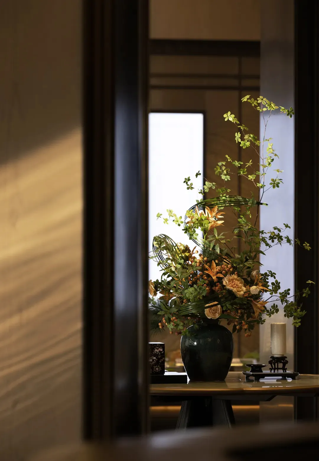 Decorative ceramic vase filled with various greenery and flowers on a table.