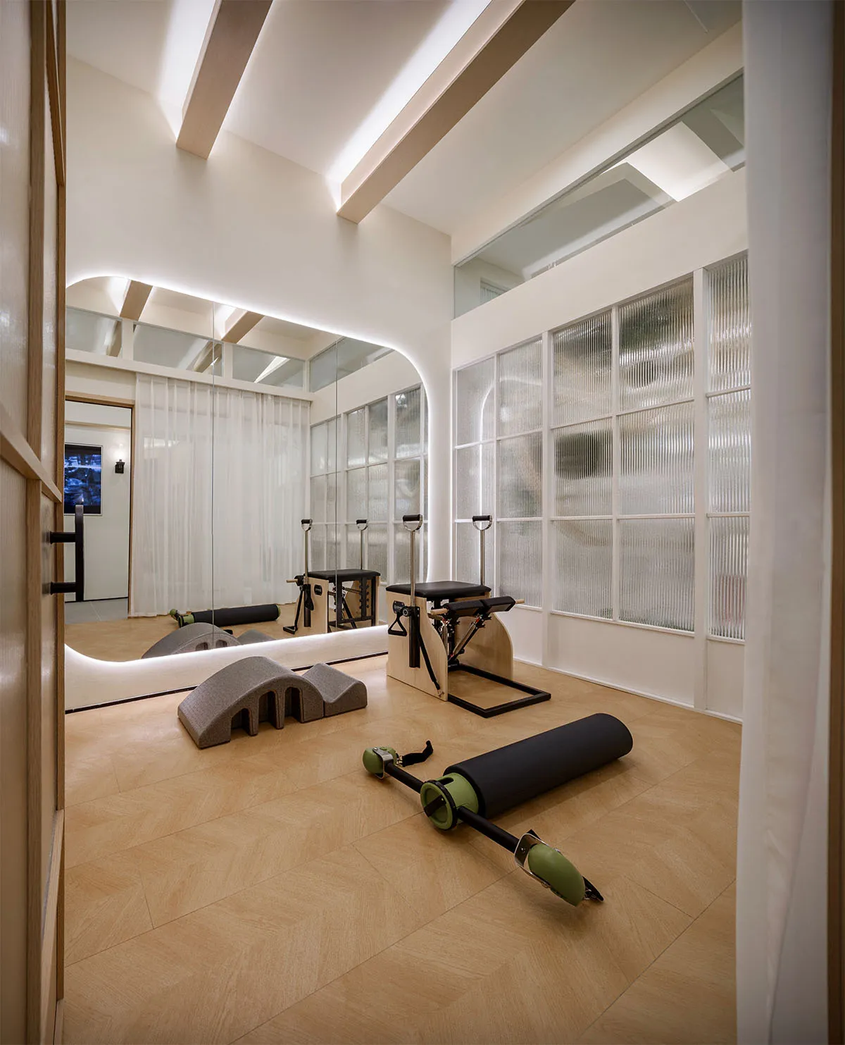 A minimalist exercise room with wooden flooring and equipment.