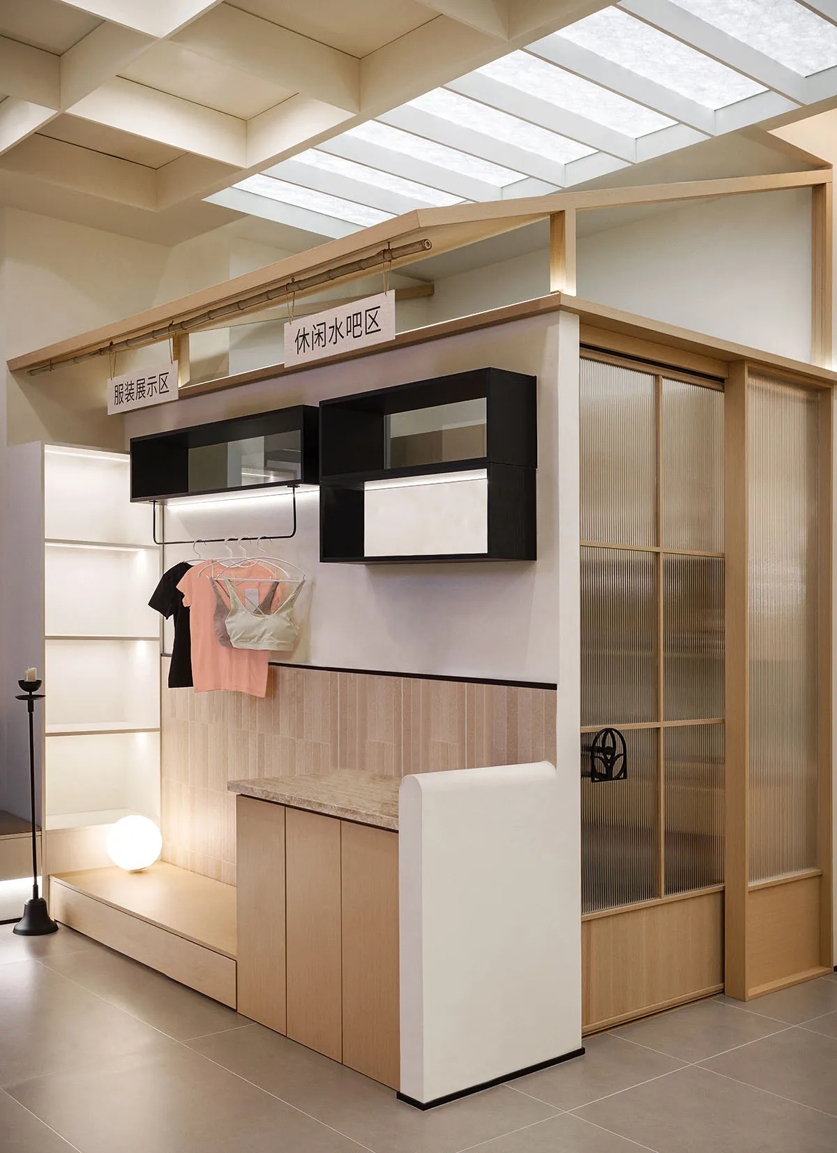 A minimalist retail storefront with a wood finish, featuring clothing racks and an illuminated storage area.