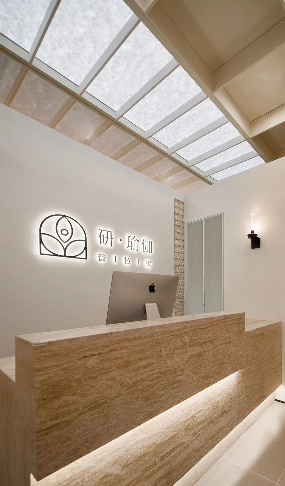 Modern reception area with a desk made of marble and glass, featuring sleek metal accents.