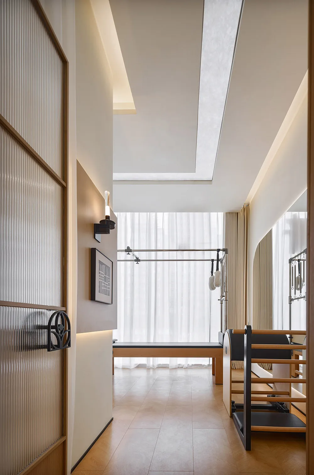 A minimalist exercise studio with wooden flooring and equipment.