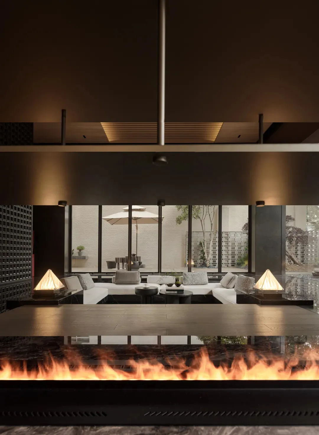 A modern living room featuring large glass walls and a cozy seating arrangement with white sofas and coffee tables.