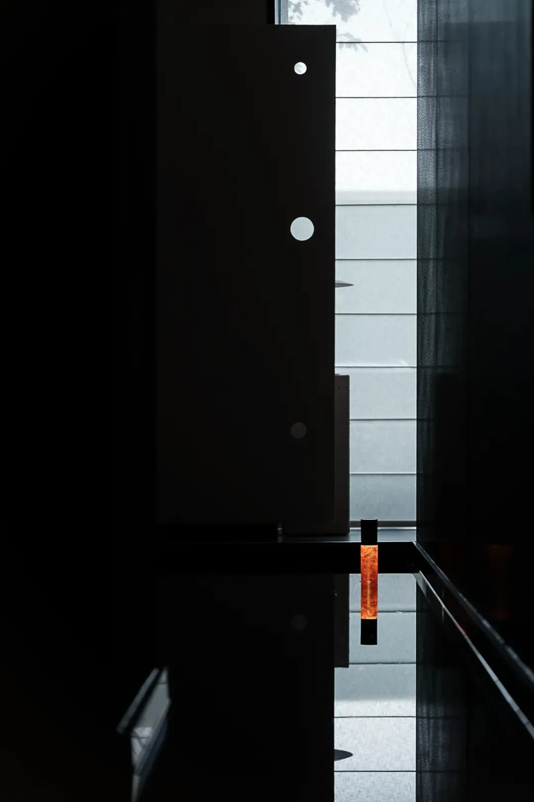 A minimalist living space featuring black glass panels and elegant, modern furnishings.