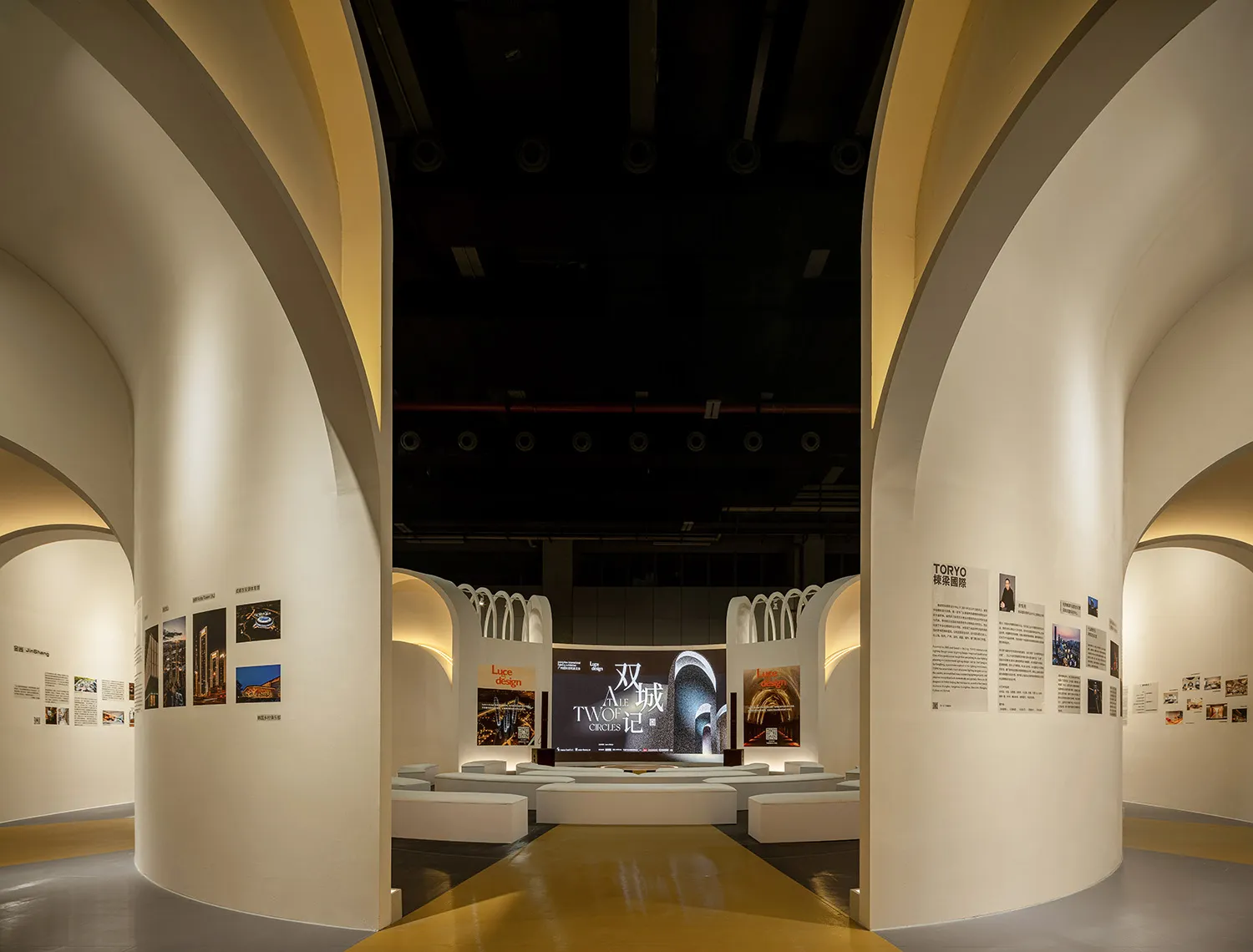 Modern exhibition space with gold accents, featuring a curved wall with artwork and a central display area.