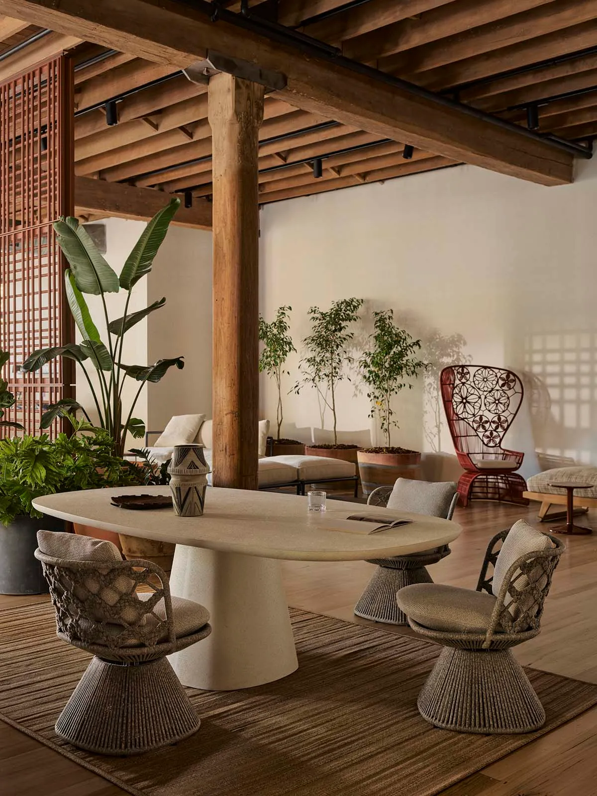 An industrial living room with wood flooring, a wooden beam, and a concrete table.