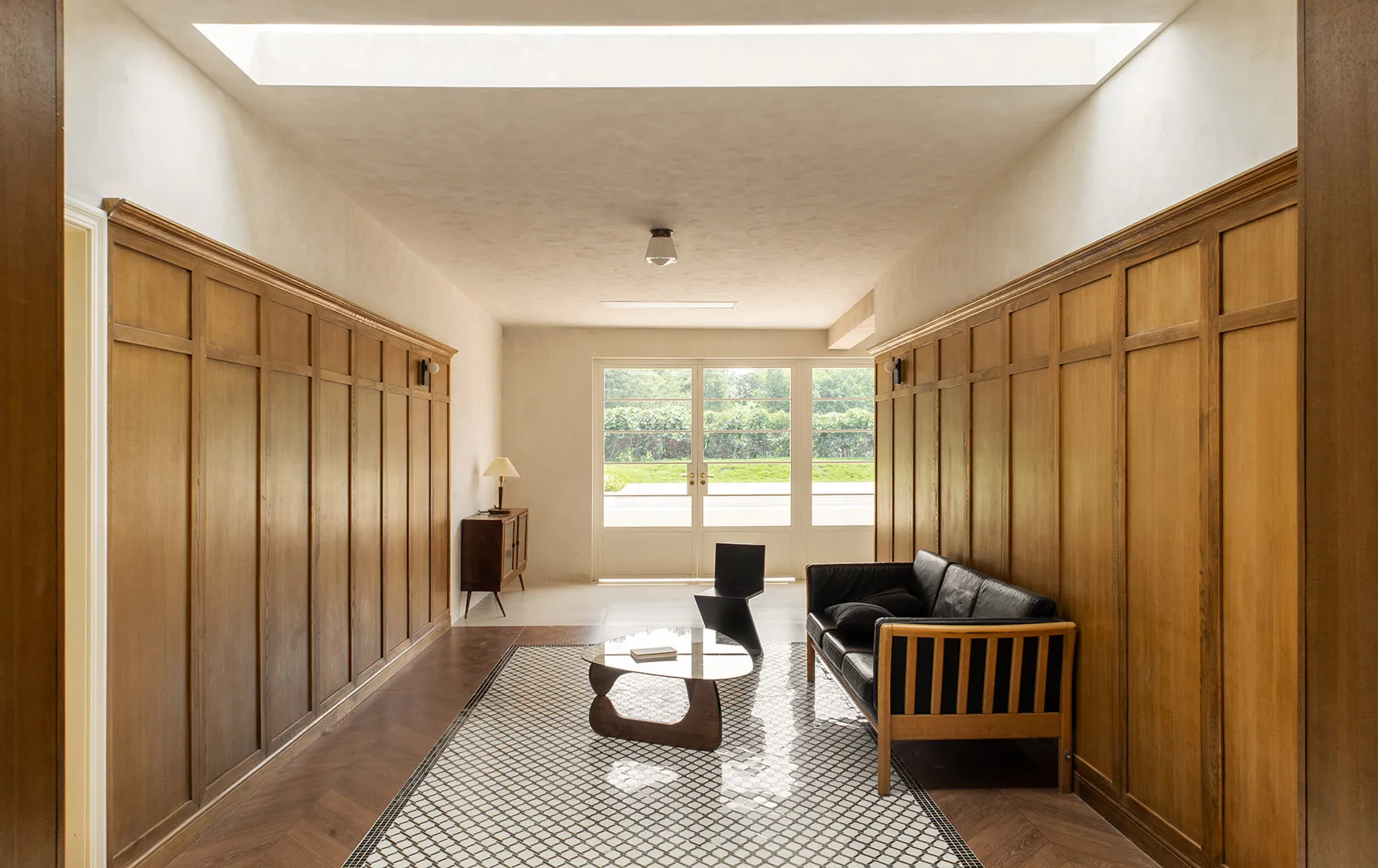 A modern lobby features wooden walls, glass walls, and a glass coffee table.
