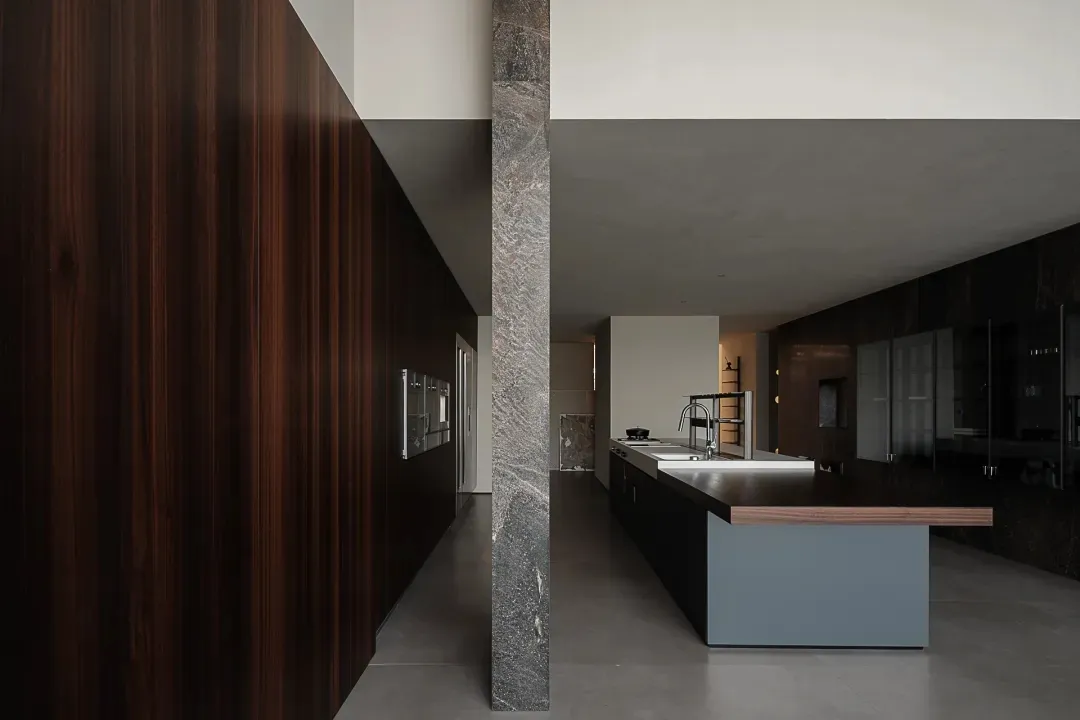 Modern residential kitchen featuring dark materials such as wood, granite, and marble.