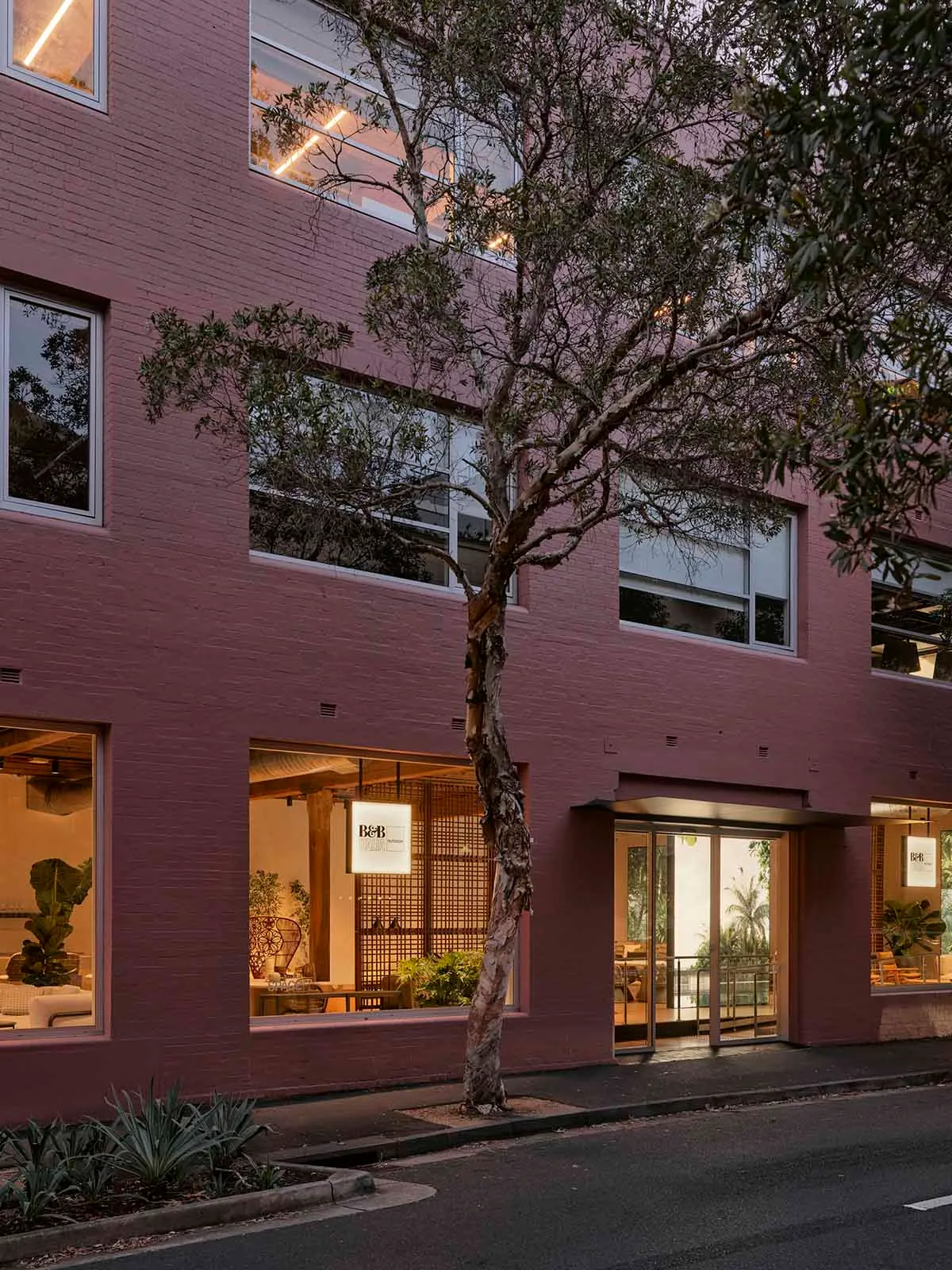 A modern retail shop with a pink brick exterior on a street corner.