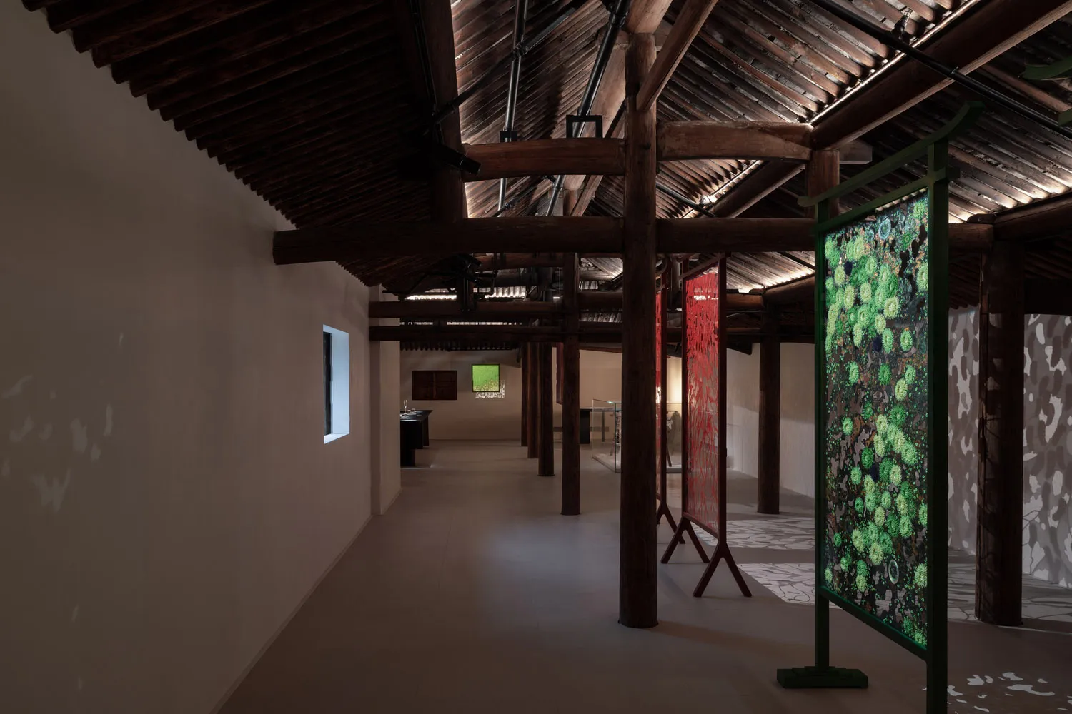 Industrial-style exhibition space featuring fabric-covered columns and intricate green patterns.