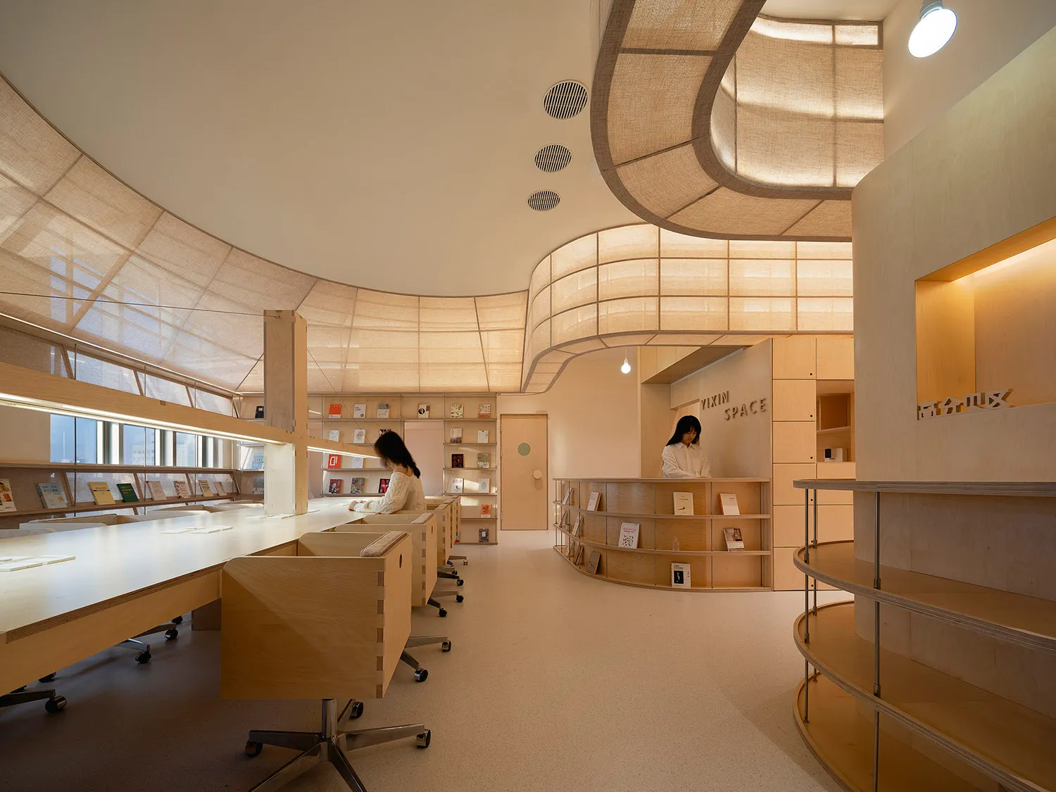 Interior of a modern library with curved wooden shelves and a minimalist design.
