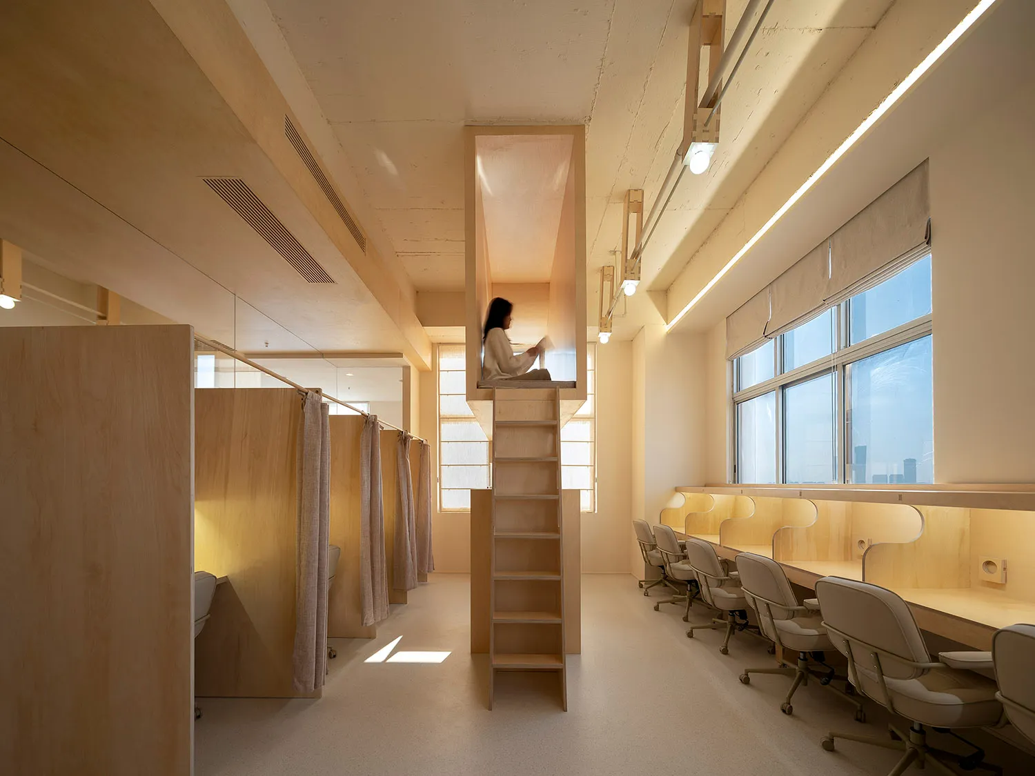 Interior of a modern minimalist coworking space with wooden furniture, desks, and natural light.