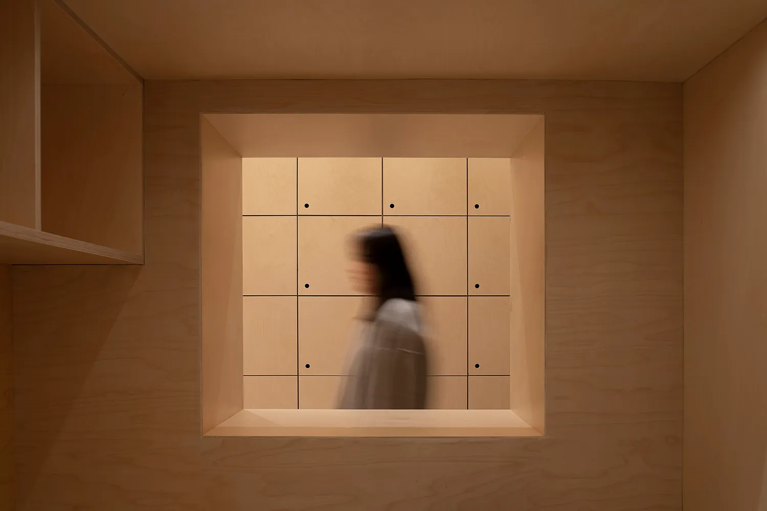 A minimalist interior space with wooden panels and a square light fixture.