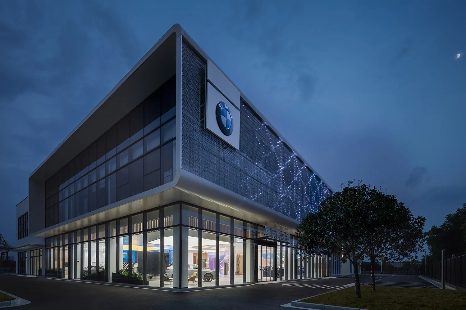 Modern office building with glass walls, concrete structure, and illuminated facade.