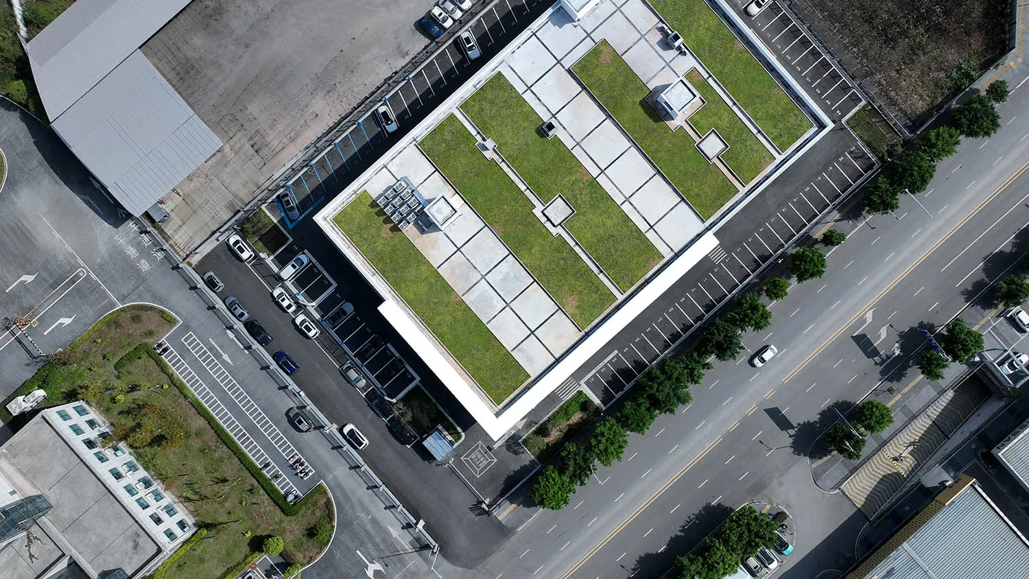 Aerial view of a modern building with a green rooftop and concrete exterior.