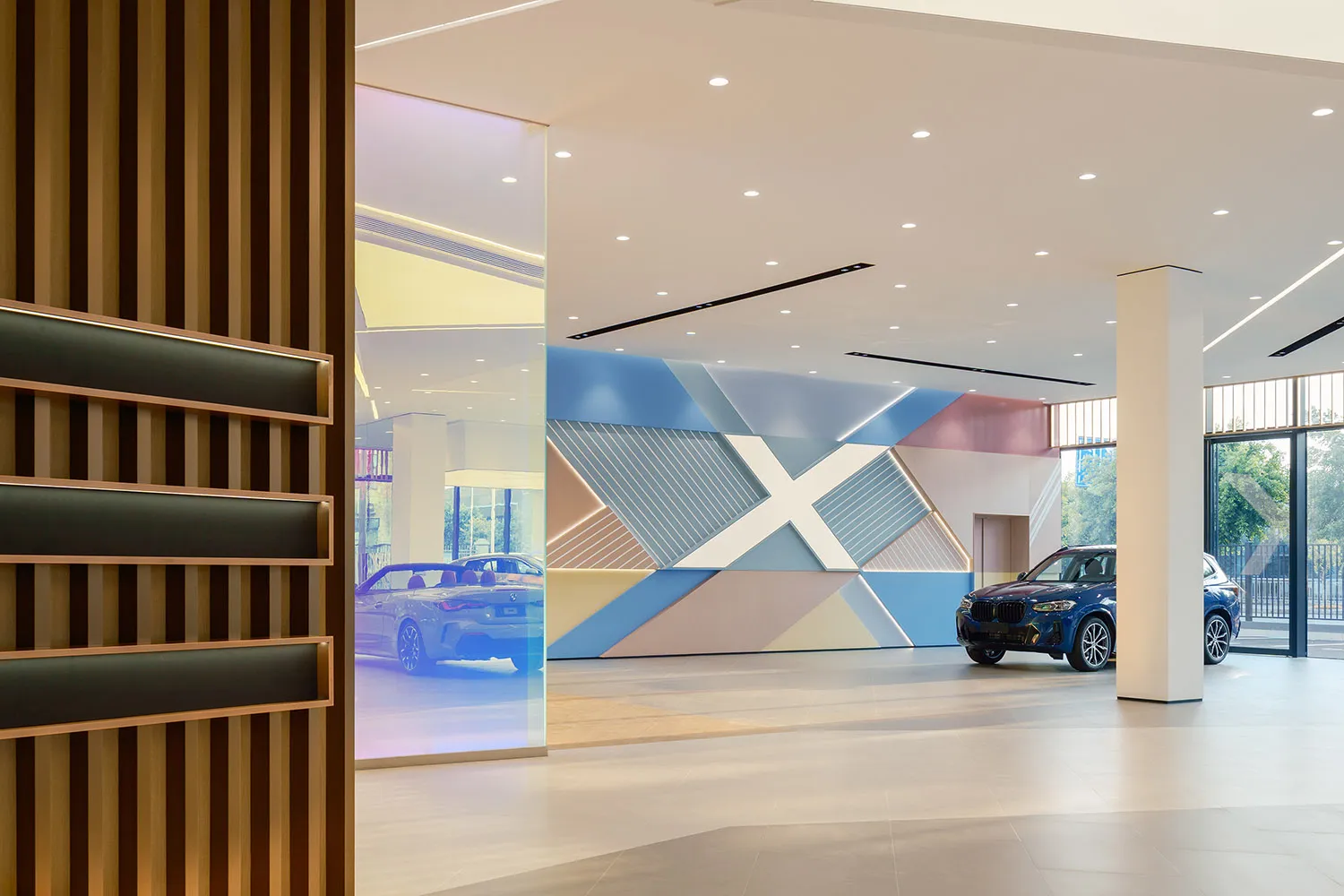 Modern auto dealership interior with colorful geometric wall and blue cars.