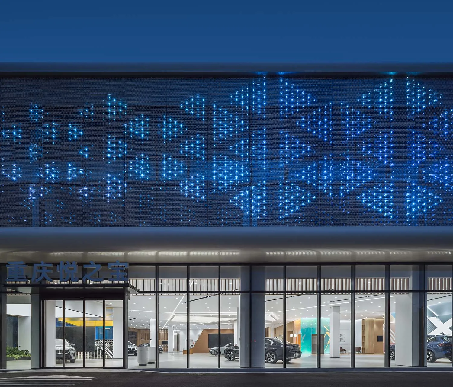 The exterior facade of a modern car dealership illuminated by LED lights.