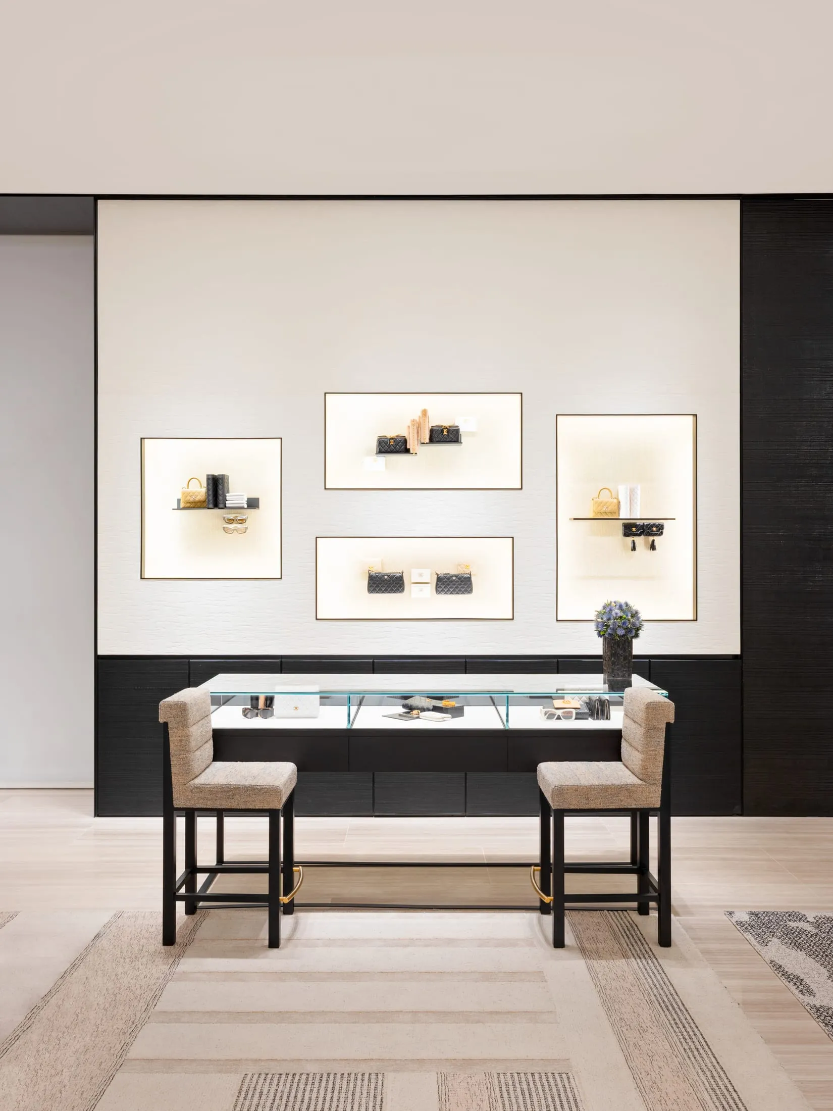 A modern retail display featuring a glass counter with various items on display, set against a polished concrete wall and sup